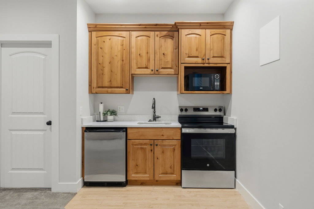 Compact kitchen area featuring wood cabinetry, a white countertop, and stainless steel appliances