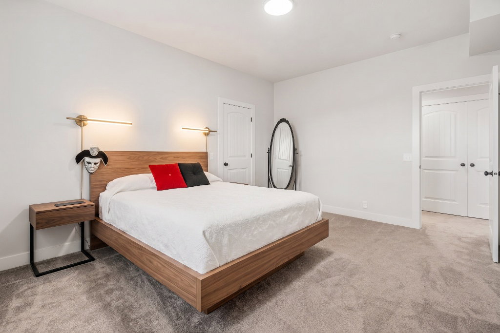 Spacious bedroom featuring light neutral wall paint, soft carpet flooring, and white trim