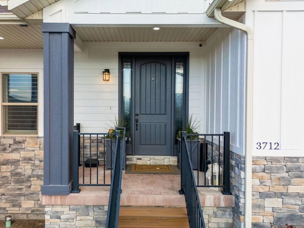 Inviting entryway with a paneled dark gray door, complementary sidelights, and a black exterior light fixture