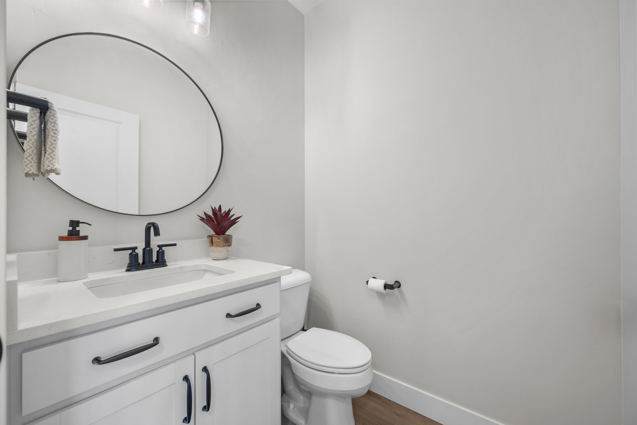 Bathroom vanity featuring a white countertop with integrated sink, matte black faucet, and white cabinetry with black hardware