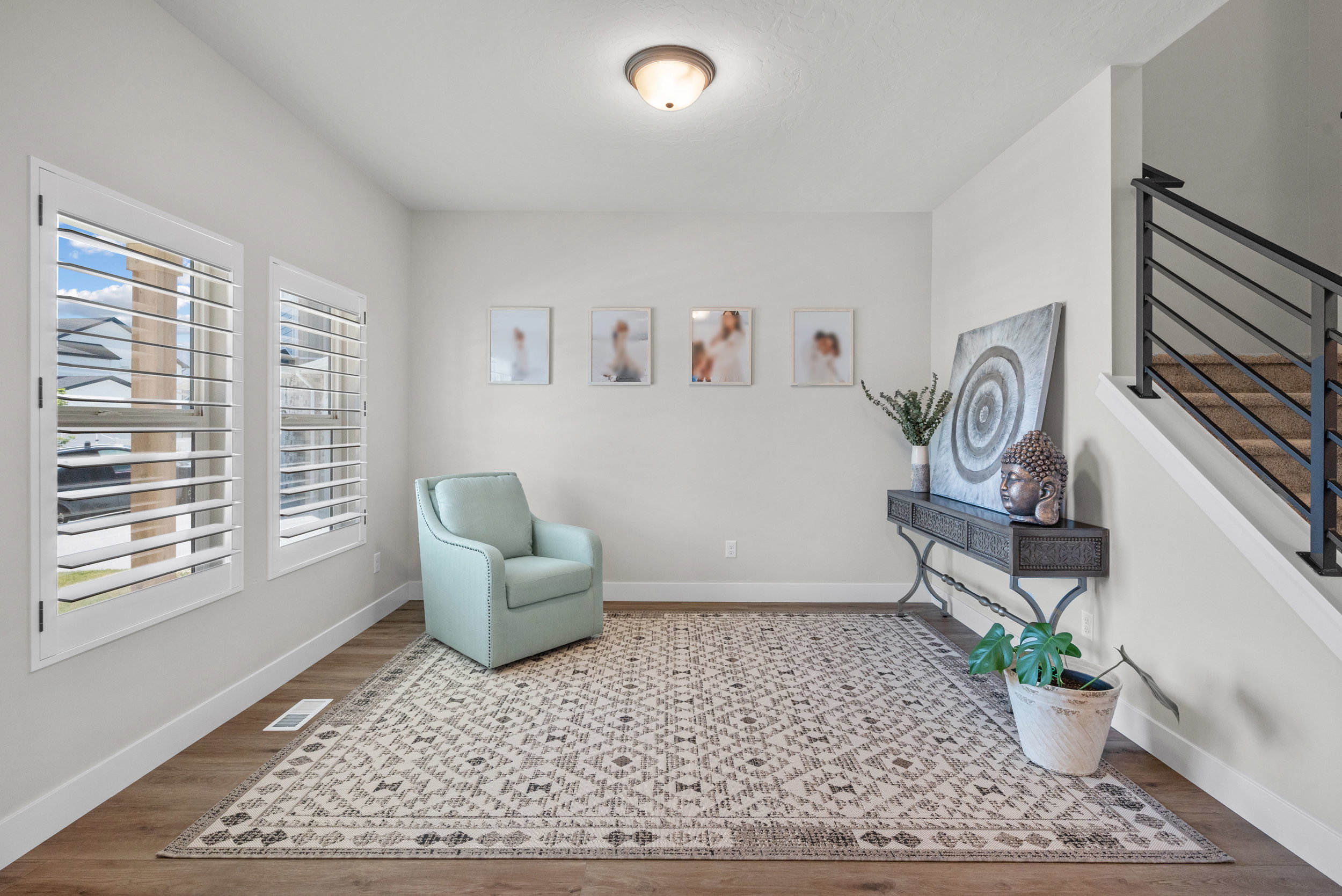 Spacious room featuring wood-finish flooring and multiple windows with plantation shutters