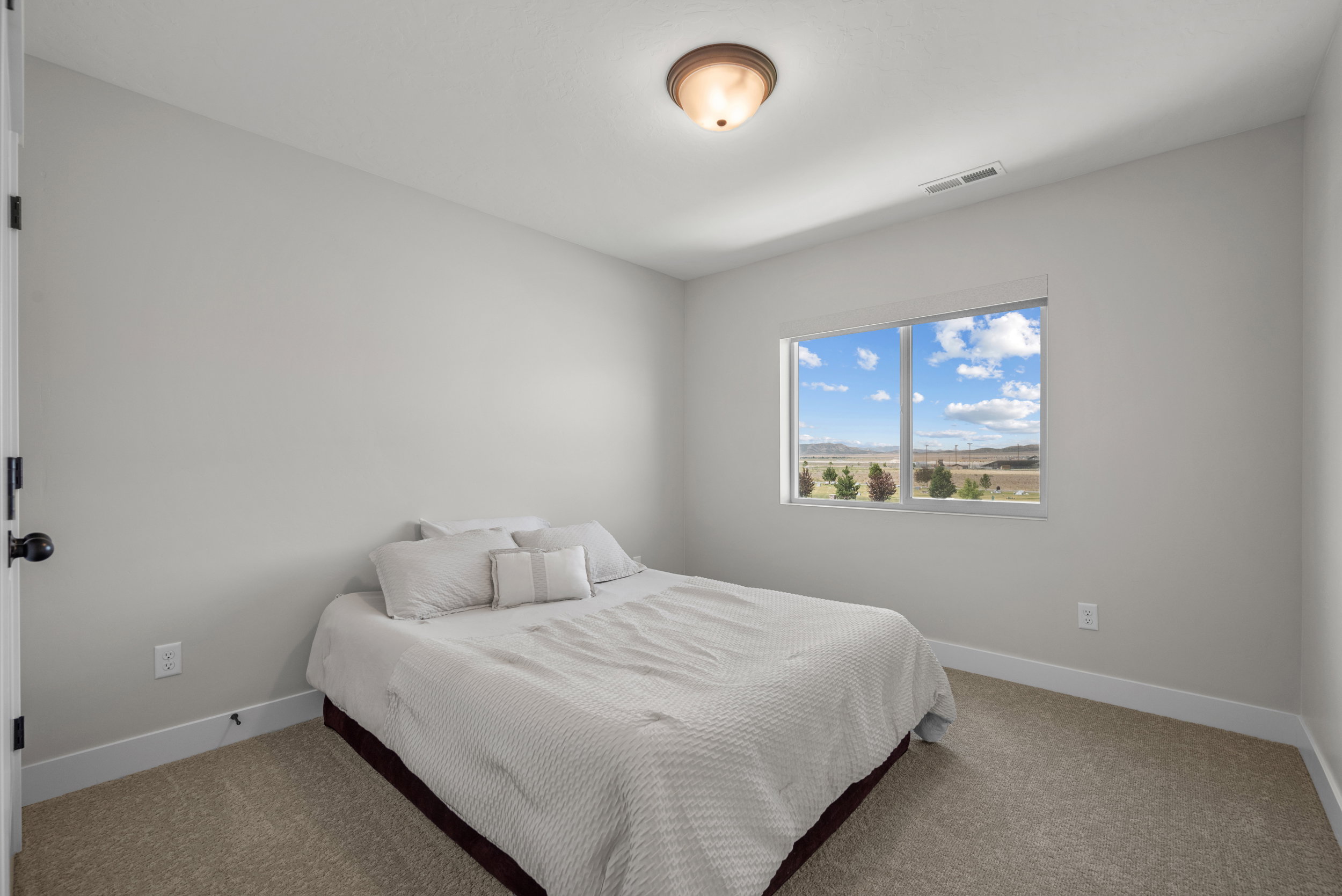 Bright room featuring light gray walls, plush carpeting, a large window, white trim, and a flush mount ceiling light fixture