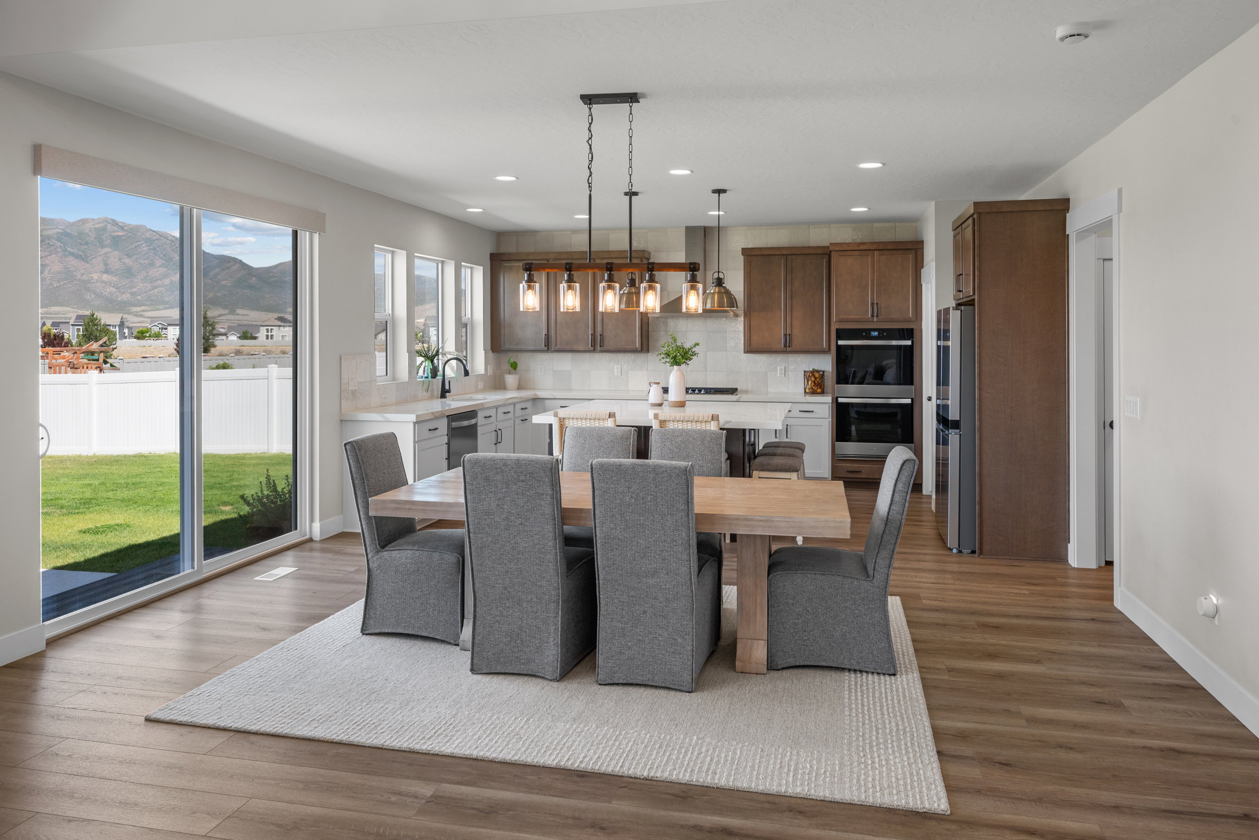 Open-concept kitchen and dining area featuring wood-finish flooring, recessed lighting, and a linear chandelier