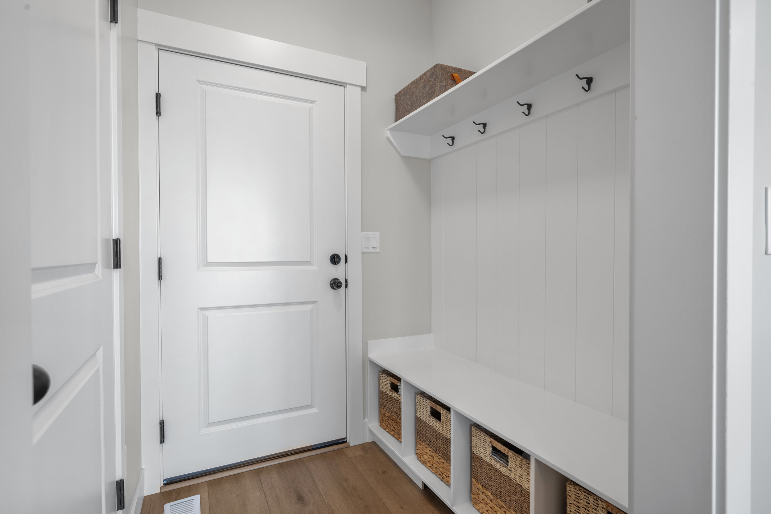 Built-in mudroom bench with cubby storage, upper shelving, and coat hooks