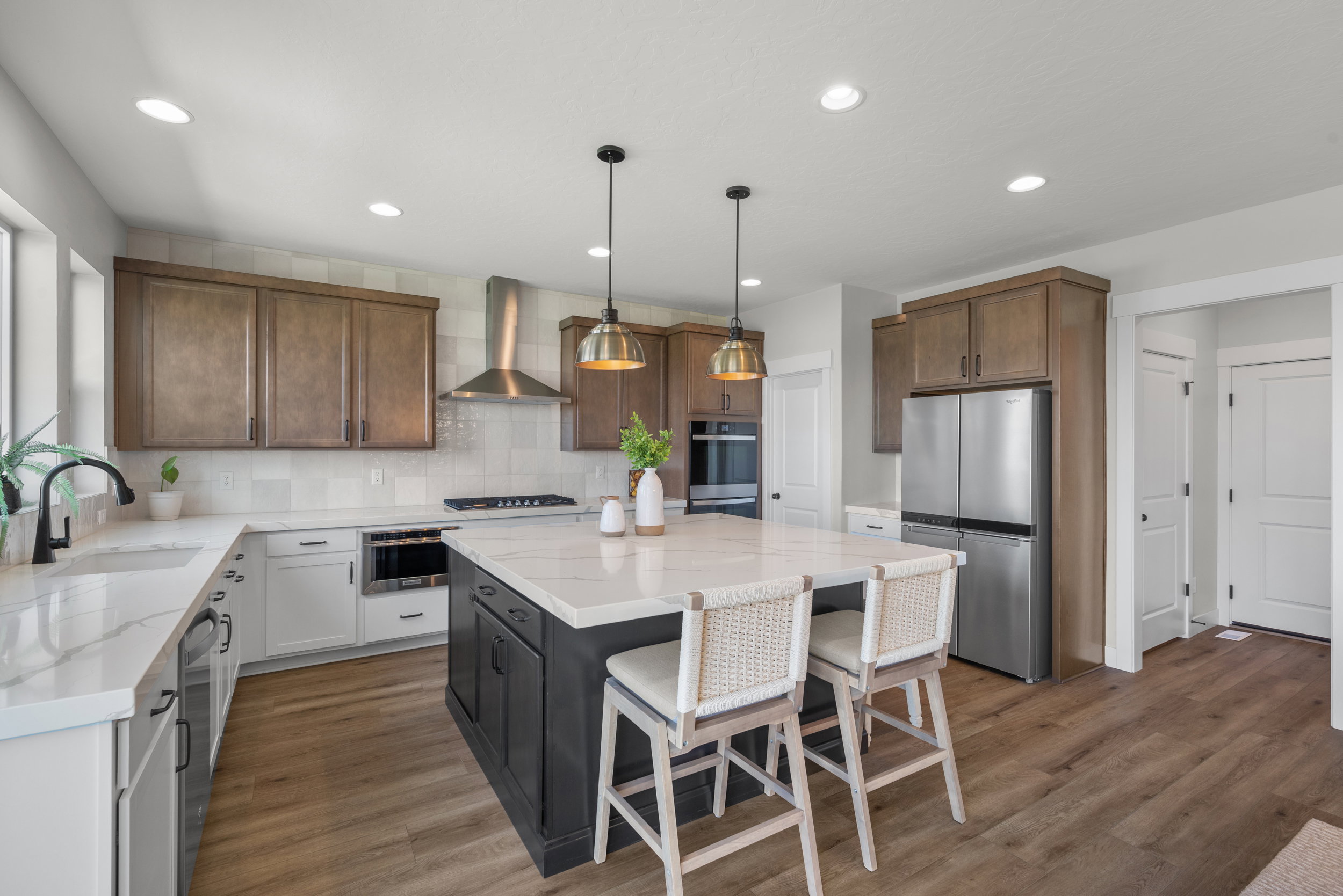 Kitchen featuring a substantial island with seating, stone countertops, integrated stainless steel appliances, wood-finish flooring, and recessed lighting