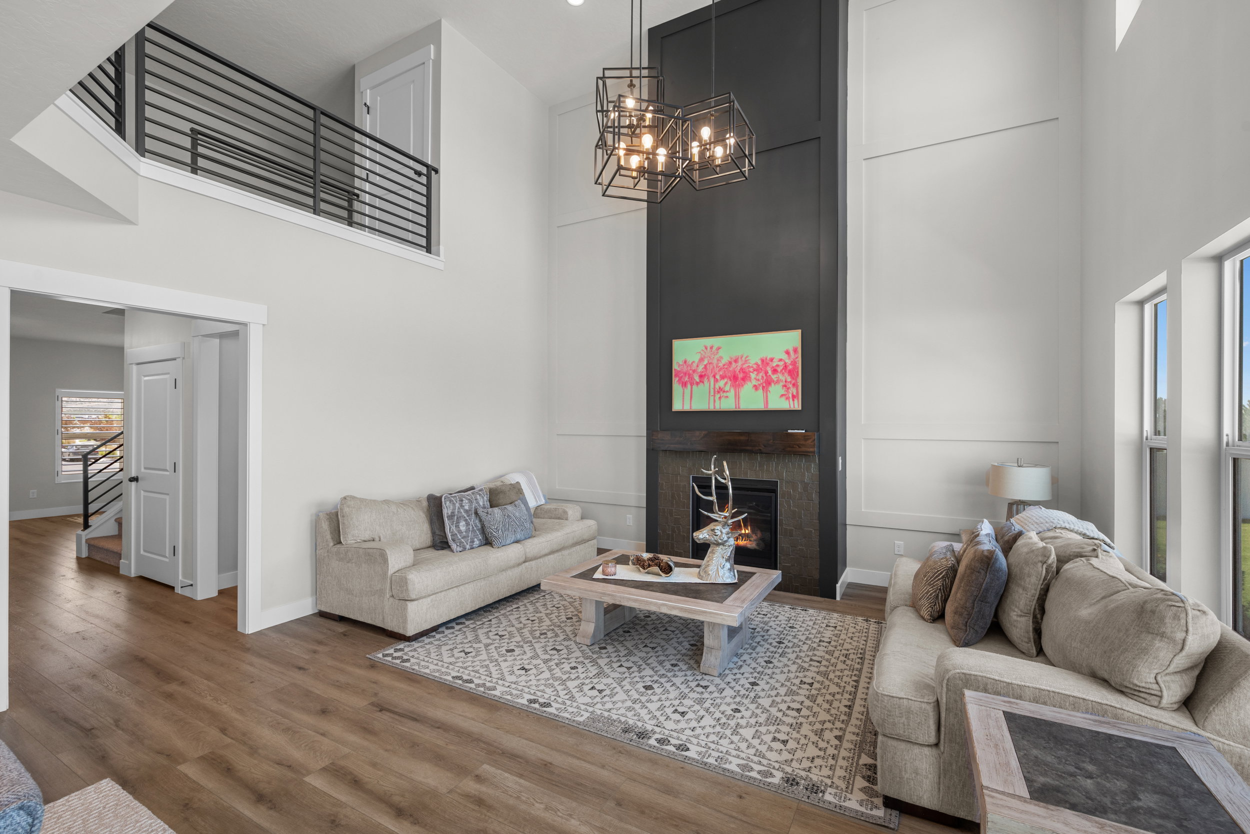 Two-story living area featuring a prominent fireplace with a dark-paneled surround, a wood mantel, and stone-look tiling