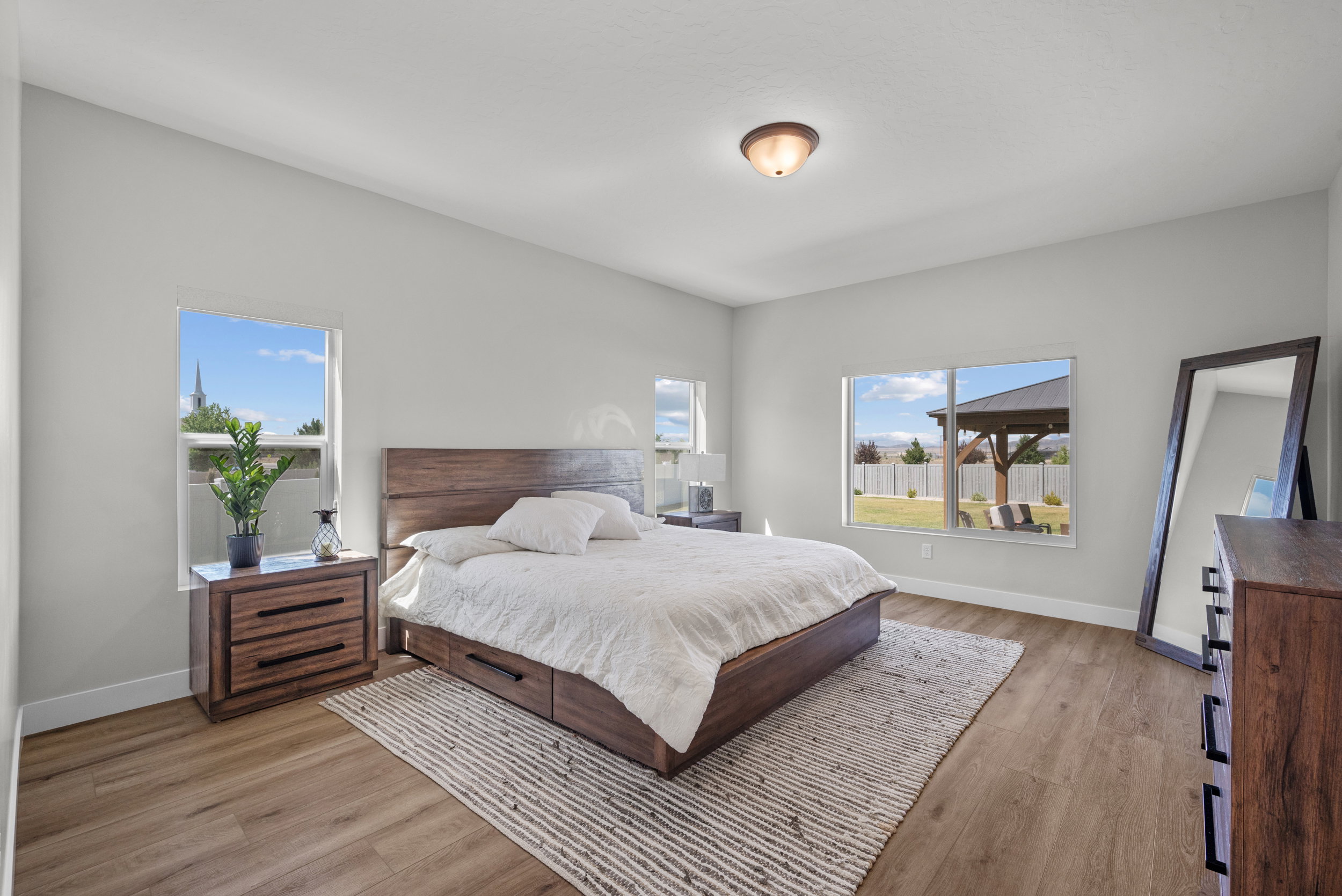 Spacious bedroom featuring light neutral wall paint and wood-finish flooring