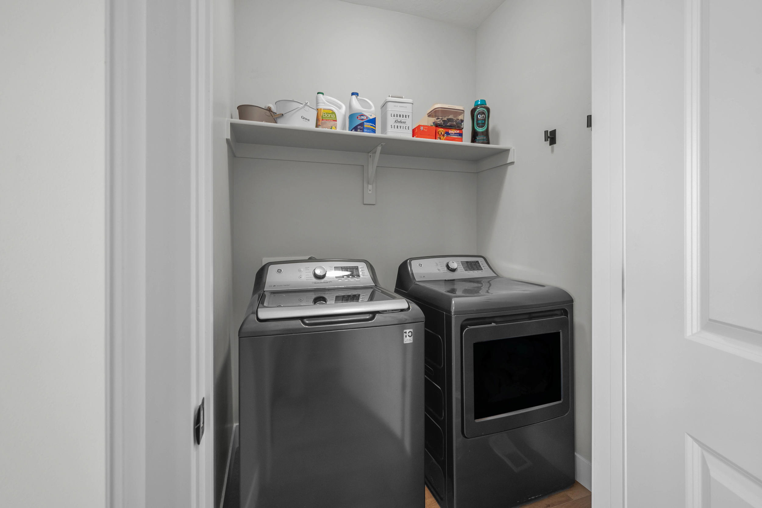 Dedicated laundry area featuring a white wall shelf for storage