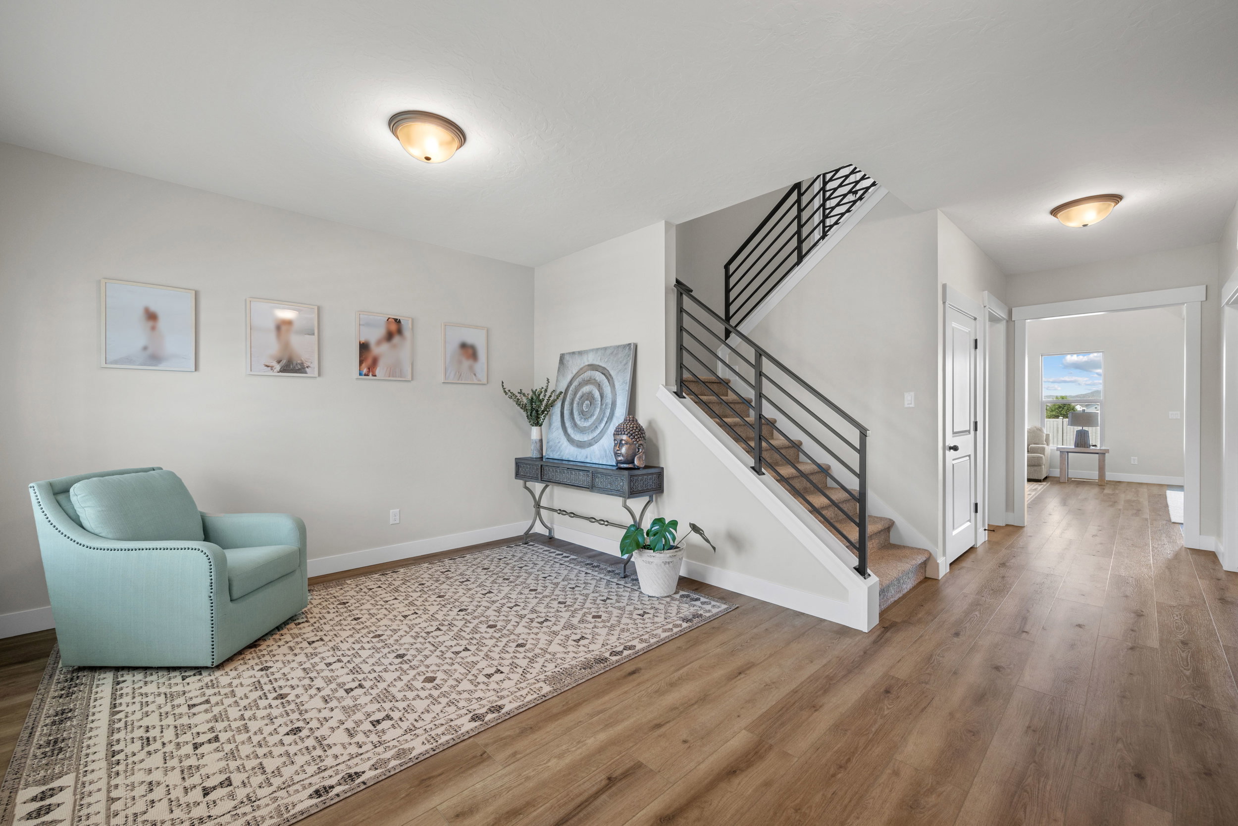 Open foyer featuring contemporary black metal horizontal stair railing, light wood-finish flooring, and neutral wall tones