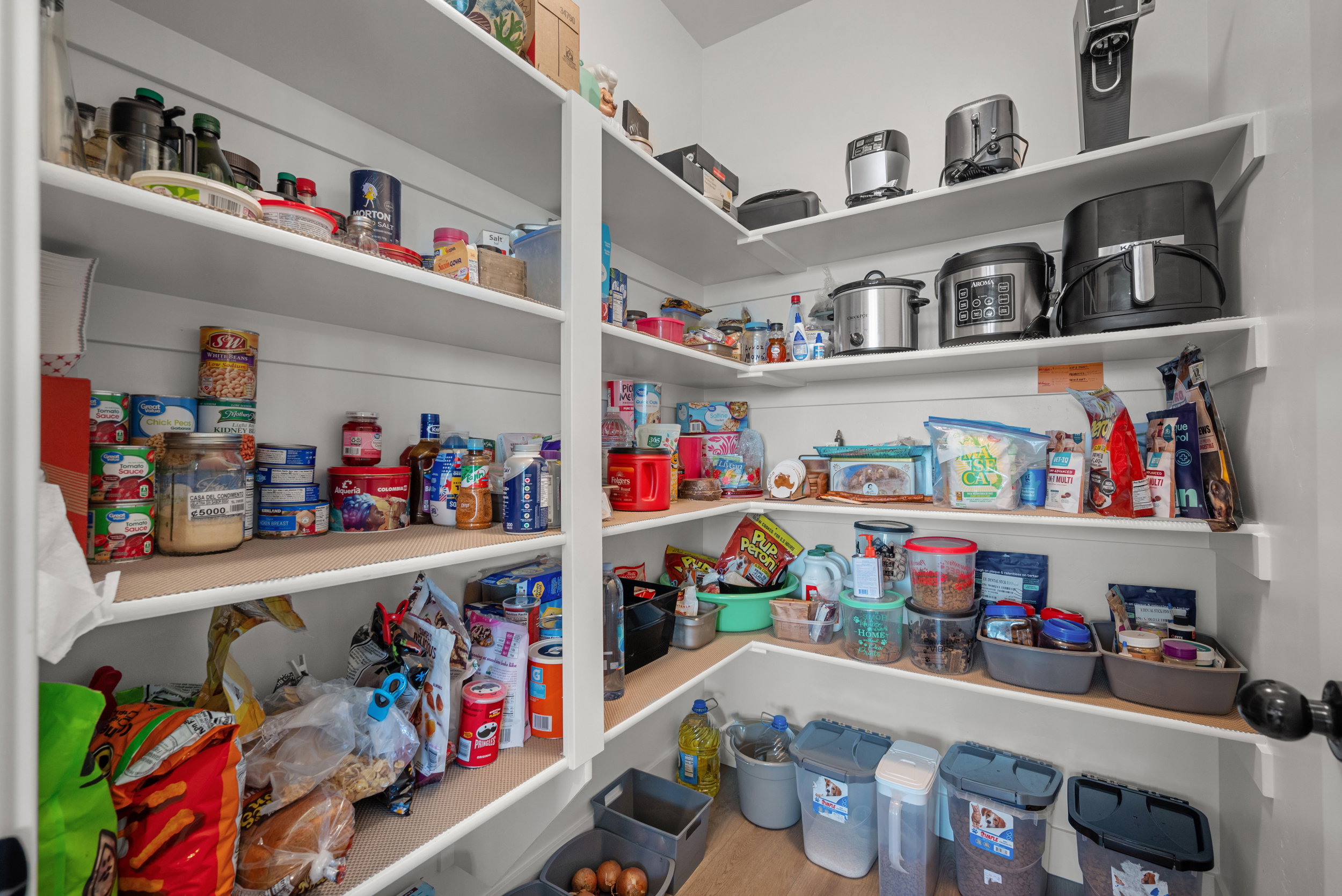 Built-in shelving providing extensive storage, white painted walls, and wood-finish flooring