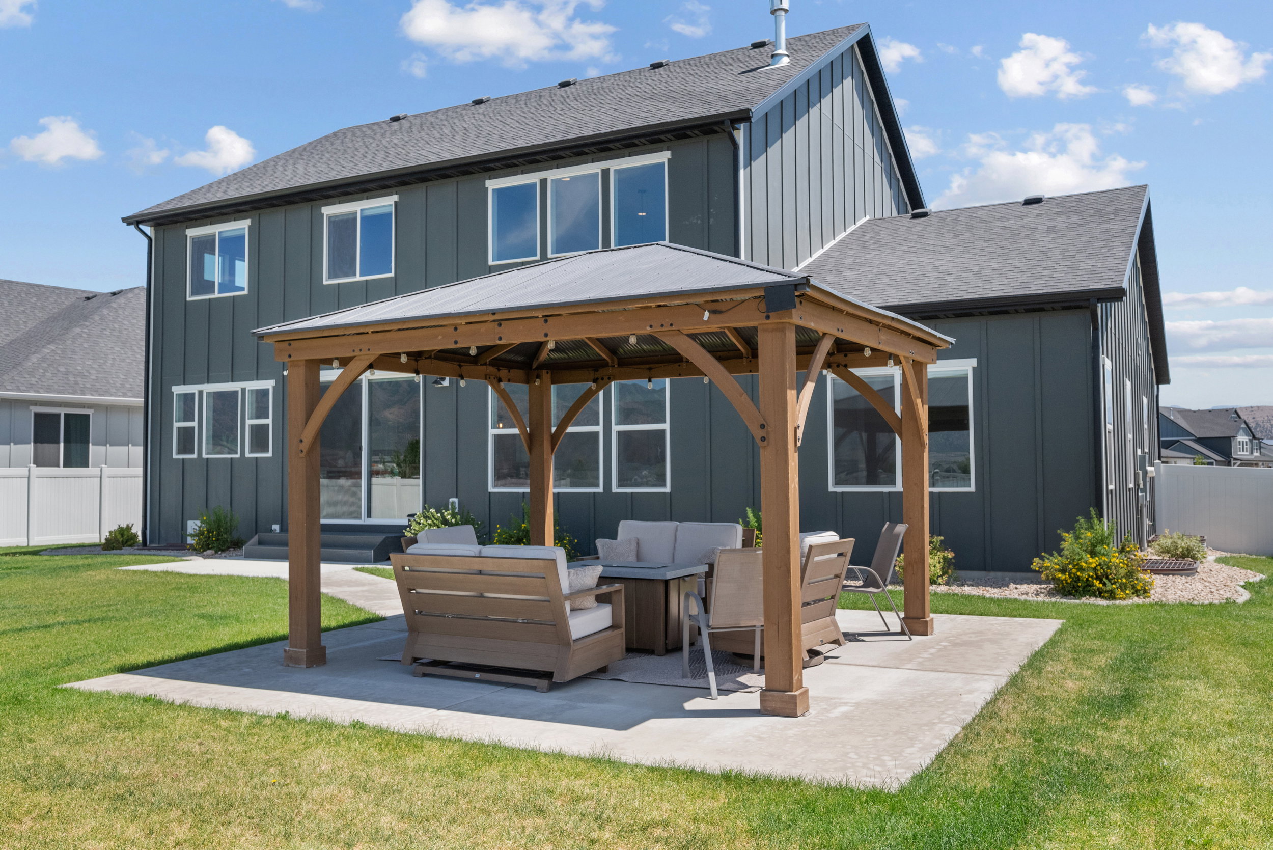 Expansive backyard featuring a gazebo on a concrete patio, a manicured lawn, and low-maintenance landscaping