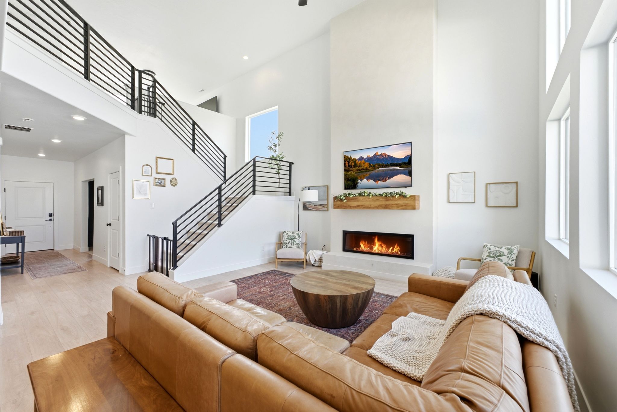 Two-story living area featuring a linear fireplace with a wood-beam mantle