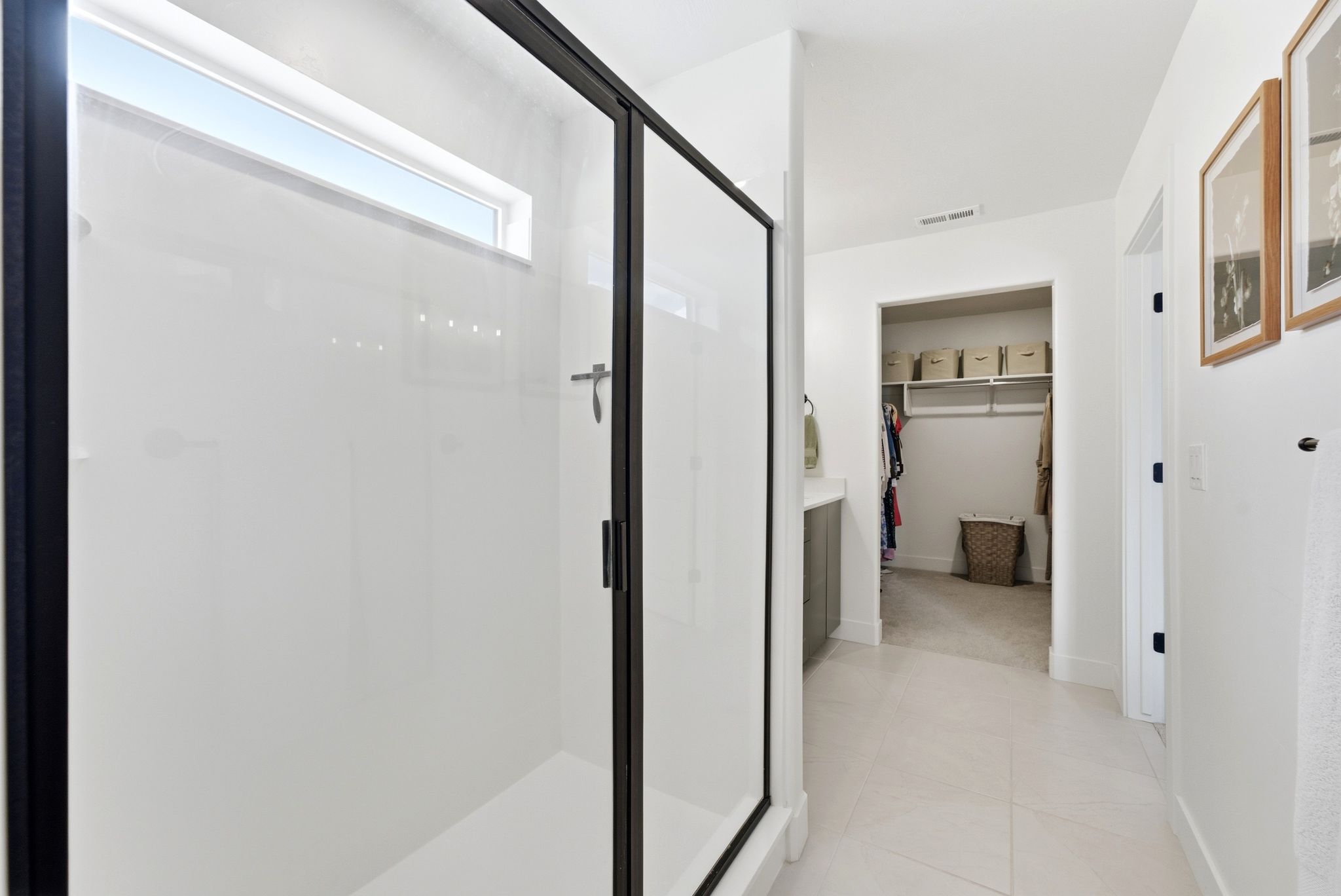 Shower enclosure with black framing, transom window, and a white shower base