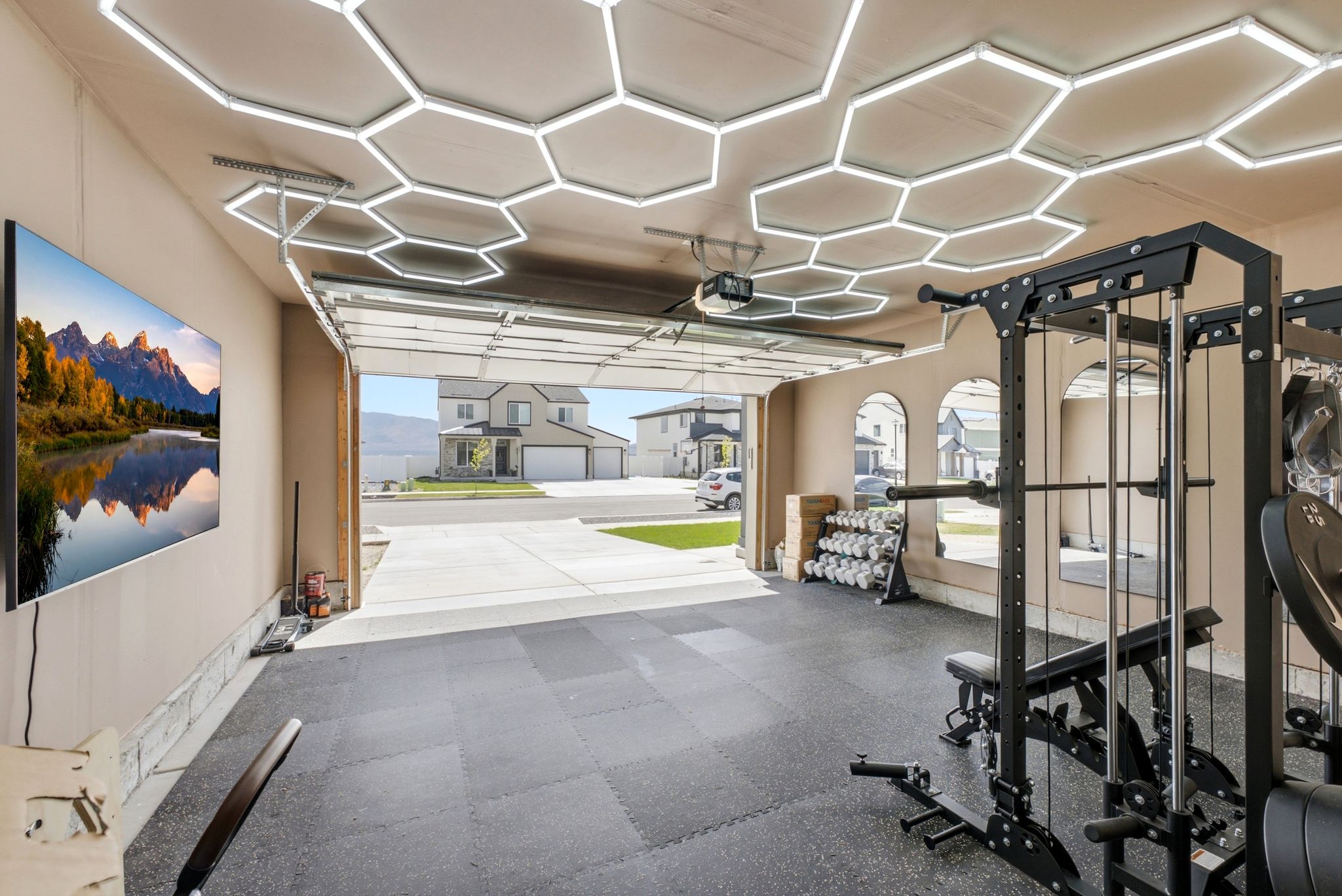 Garage interior featuring hexagonal ceiling lighting, tiled rubber flooring, and an arched mirror installation