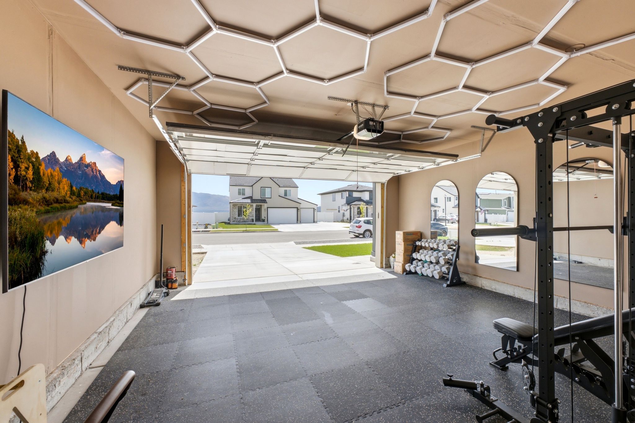 Garage space featuring durable rubber flooring, integrated ceiling lighting, and a wall-mounted display
