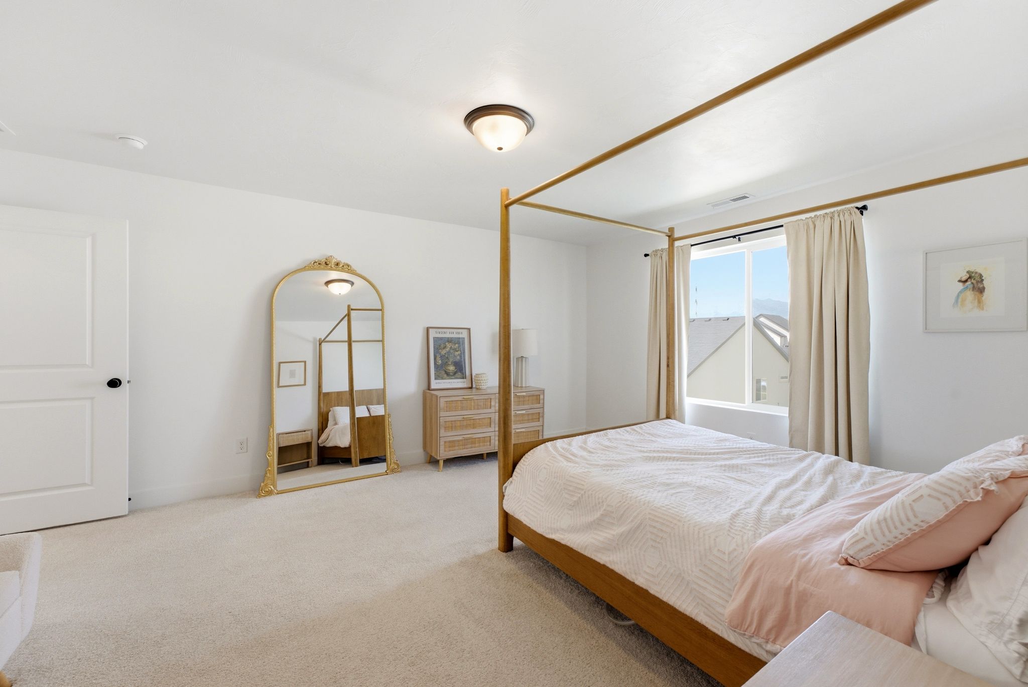 Carpeted bedroom featuring a large window with mountain scenery, white walls, a flush-mount ceiling light fixture, and a solid white door with black hardware