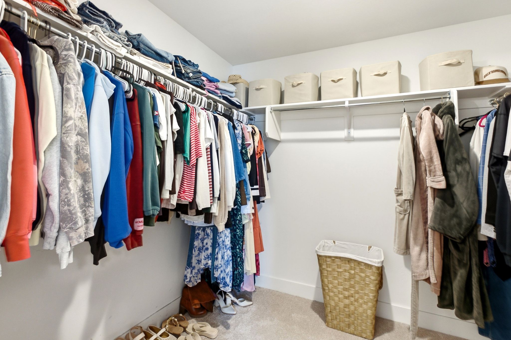 Spacious walk-in closet featuring white wall-mounted shelving and multiple clothing rods for extensive storage