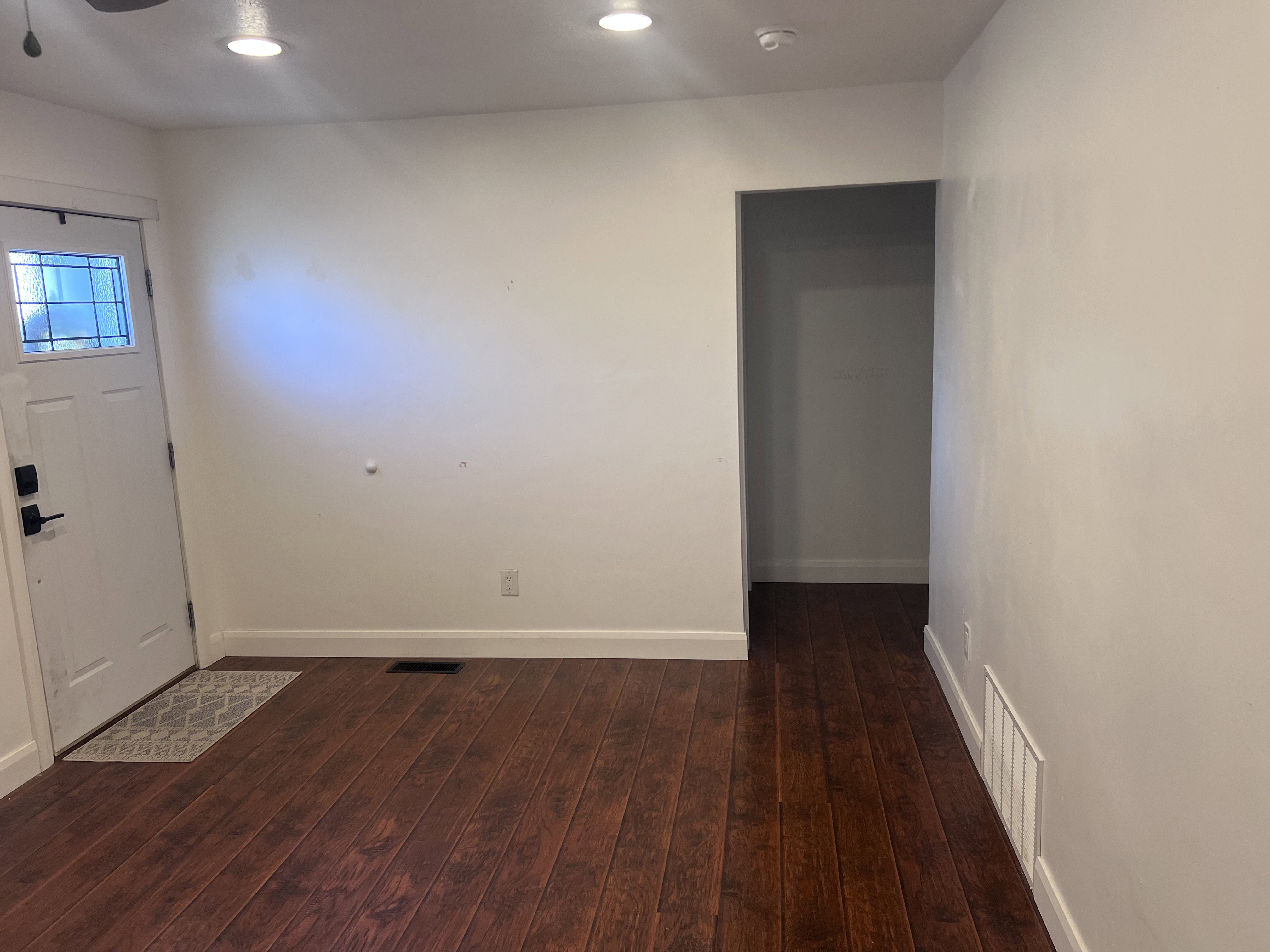 Entryway with dark wood-finish flooring and a white door featuring a decorative glass insert