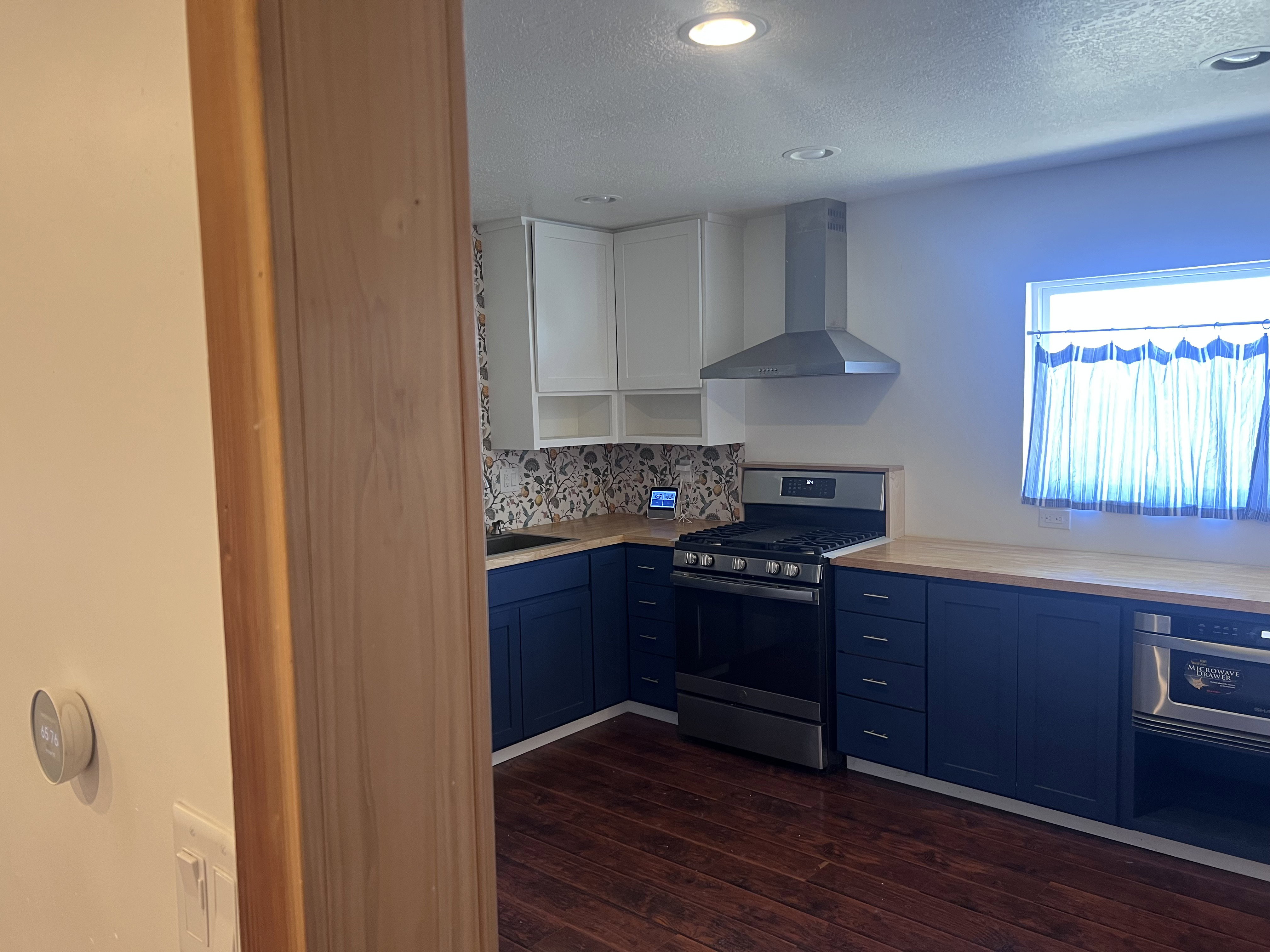 Modern kitchen featuring two-tone cabinetry, stainless steel appliances, wood-finish countertops, and recessed lighting