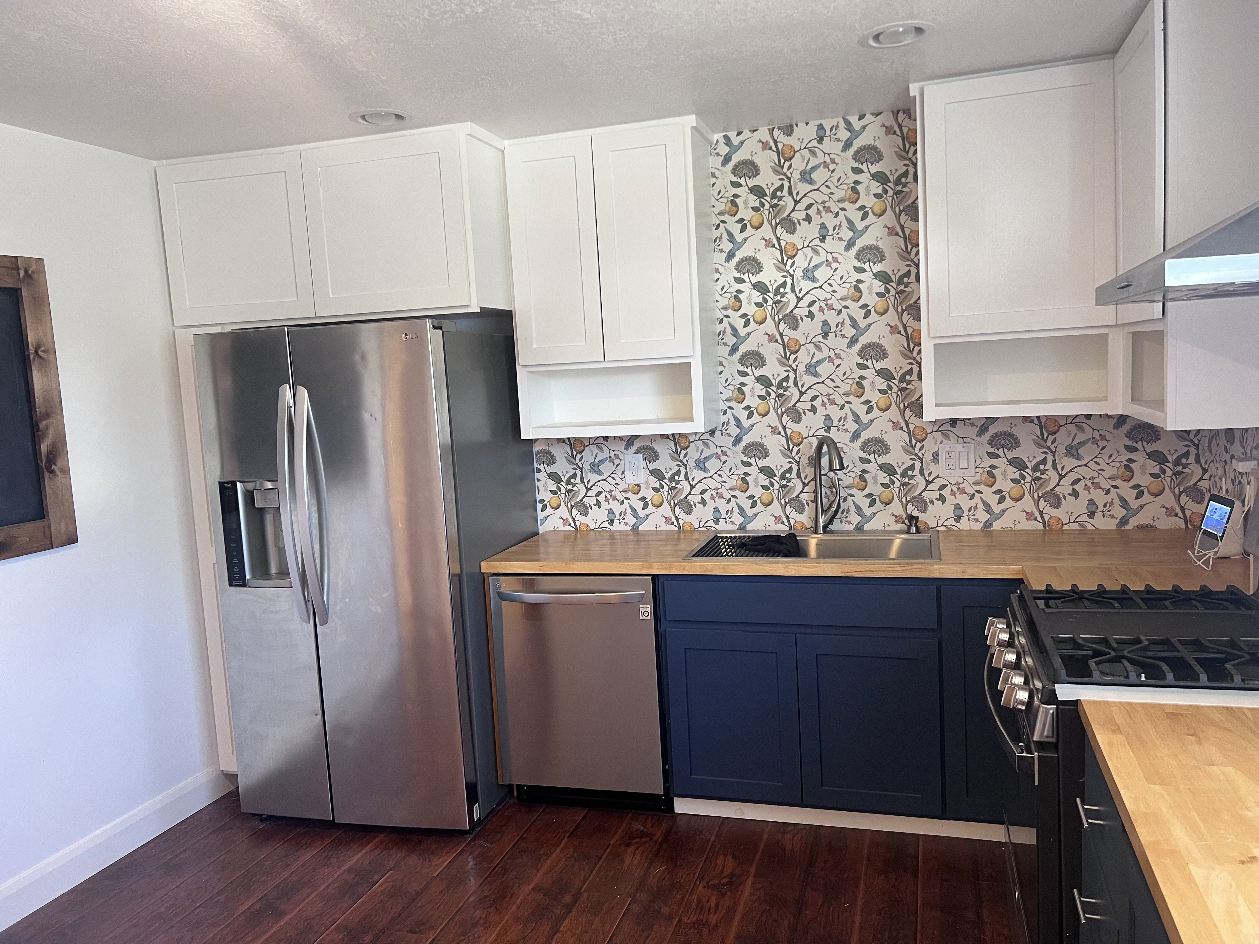 Kitchen featuring wood-finish flooring, white upper cabinetry, and contrasting navy lower cabinetry