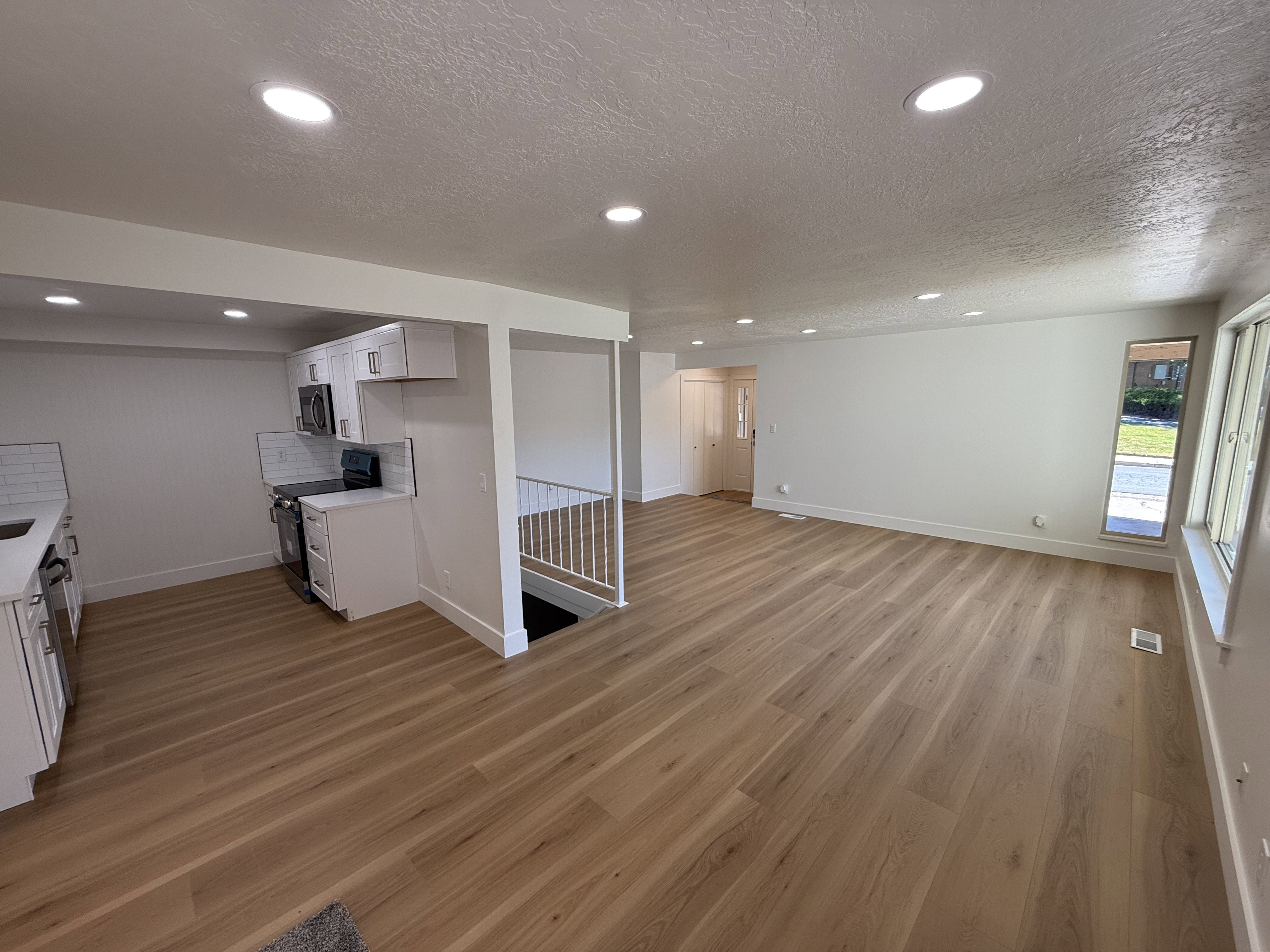 Open-concept living space featuring wood-finish flooring, recessed lighting, and white walls