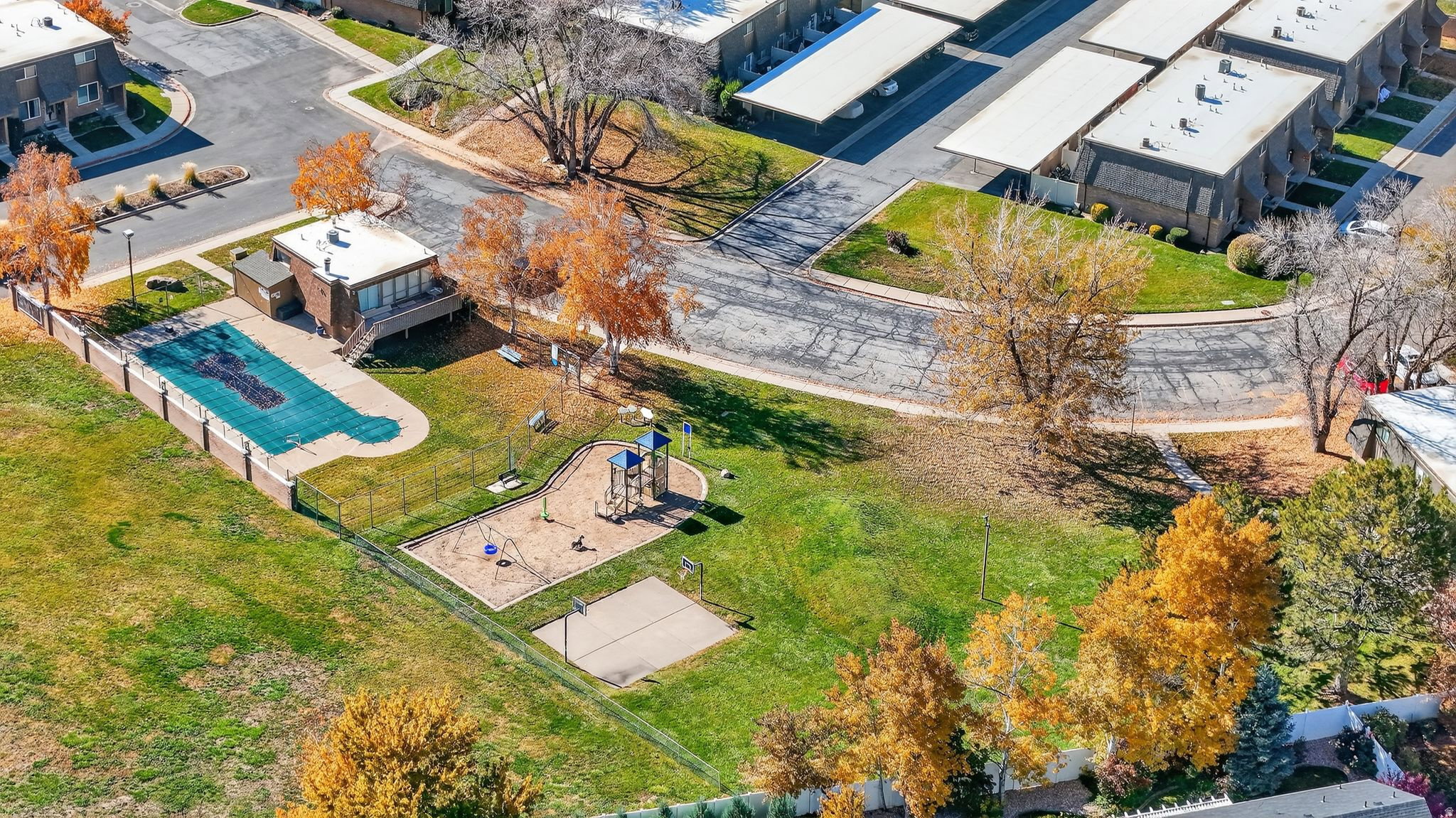 Community amenities featuring a fenced pool area, adjacent clubhouse, and a playground with a sandbox area