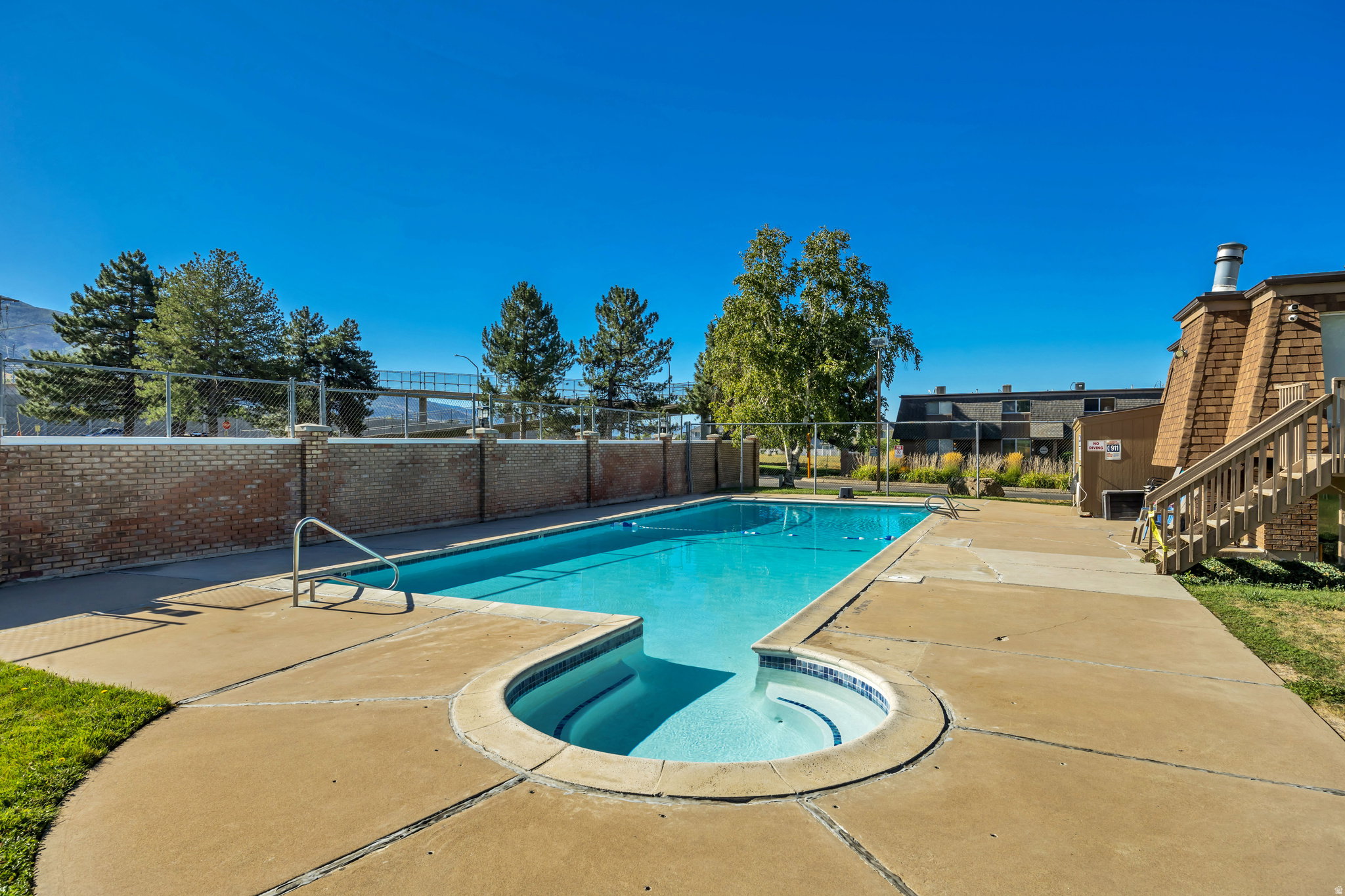 Outdoor swimming pool with integrated spa and concrete surround