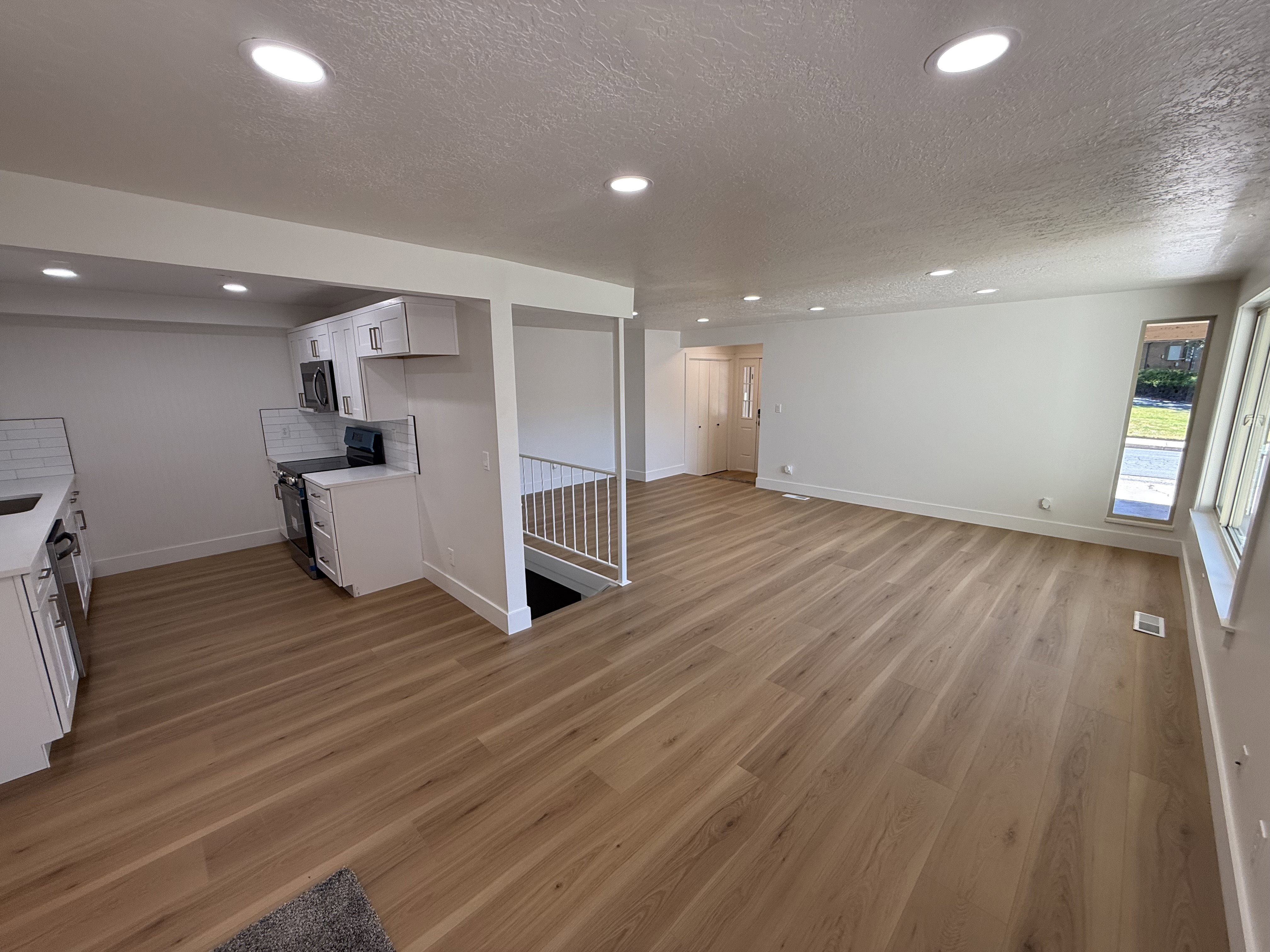 Open-concept living space featuring wood-finish flooring, recessed lighting, and white walls