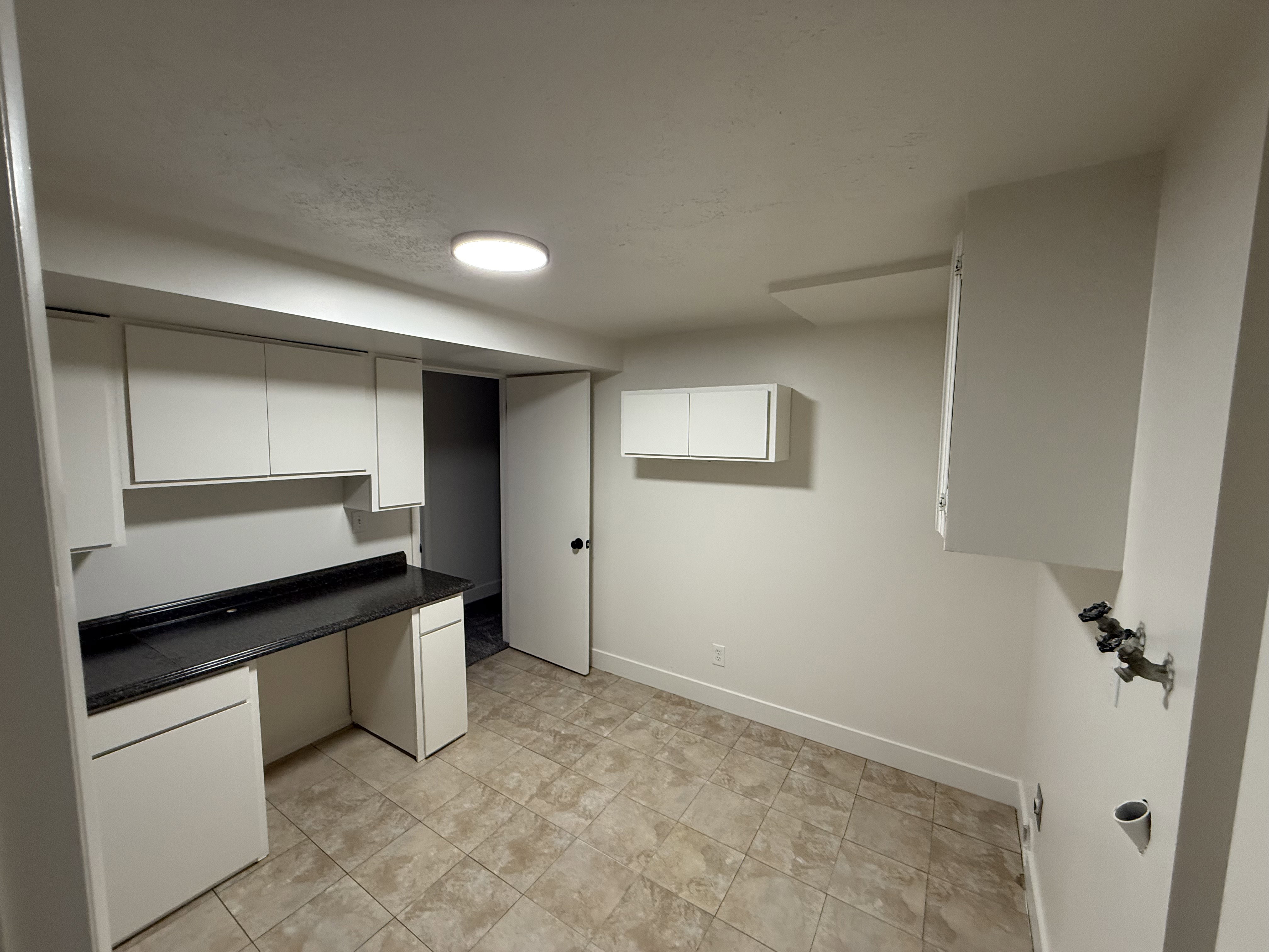 Utility room featuring tile flooring, white cabinetry, a dark speckled countertop, and laundry hookups