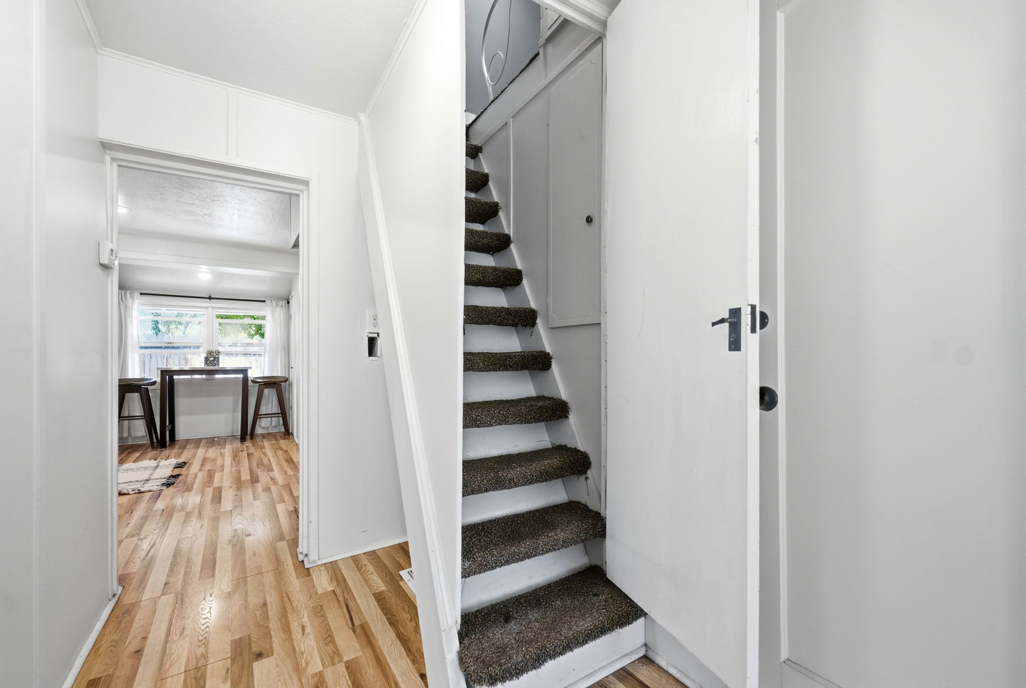 Carpeted staircase with white risers and a wood-finish flooring entryway