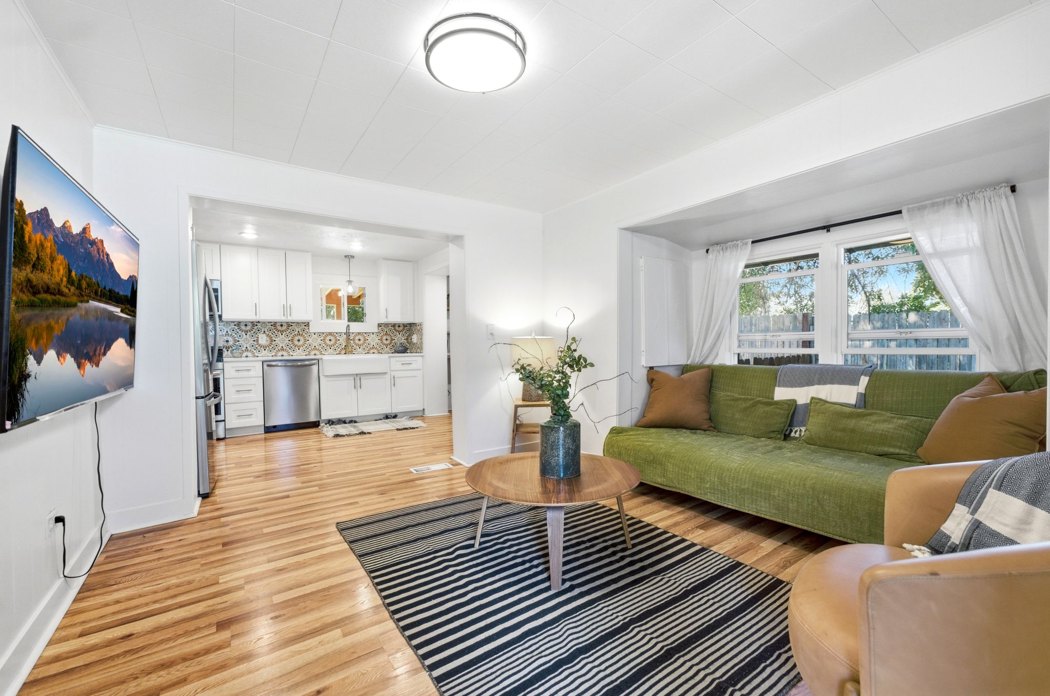 Open-concept living area with wood-finish flooring, recessed lighting, and a kitchen pass-through