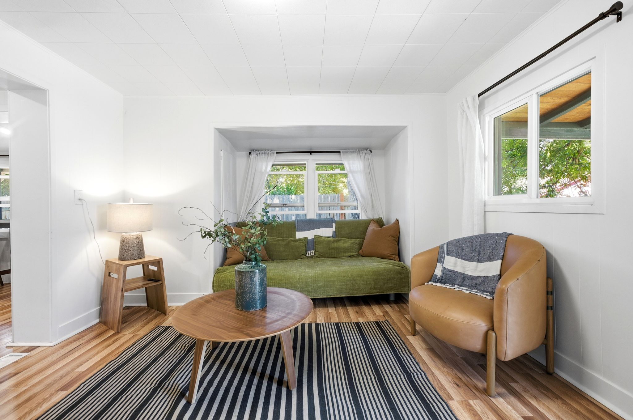 Bright living area featuring wood-finish flooring, white walls, and a recessed window nook