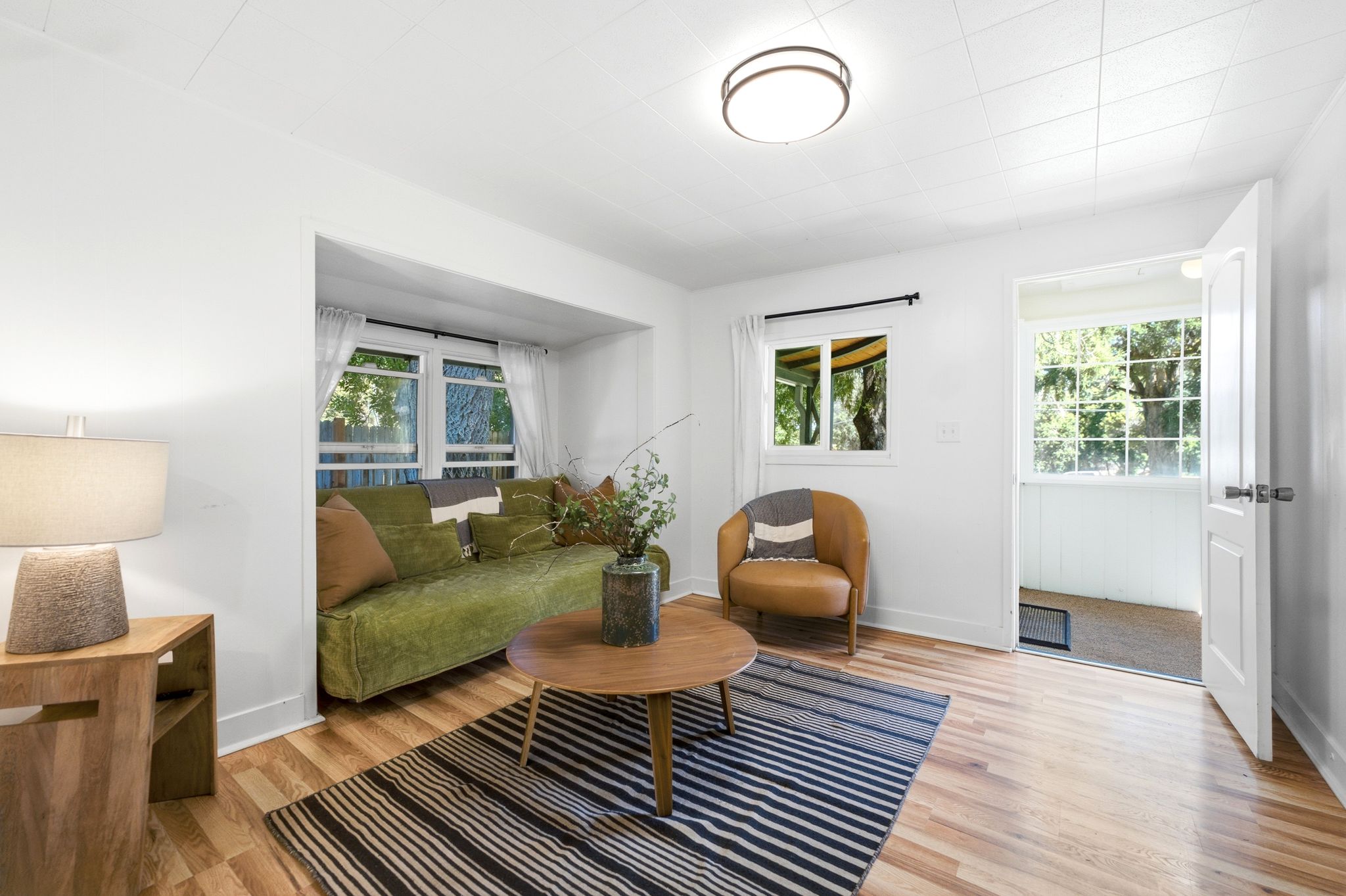 Living area featuring wood-finish flooring, white walls, a built-in window nook, a flush-mount ceiling light fixture, and multiple windows