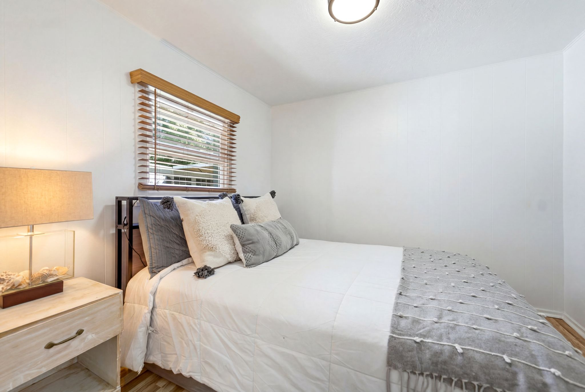 White walls and wood-finish flooring define this bedroom space