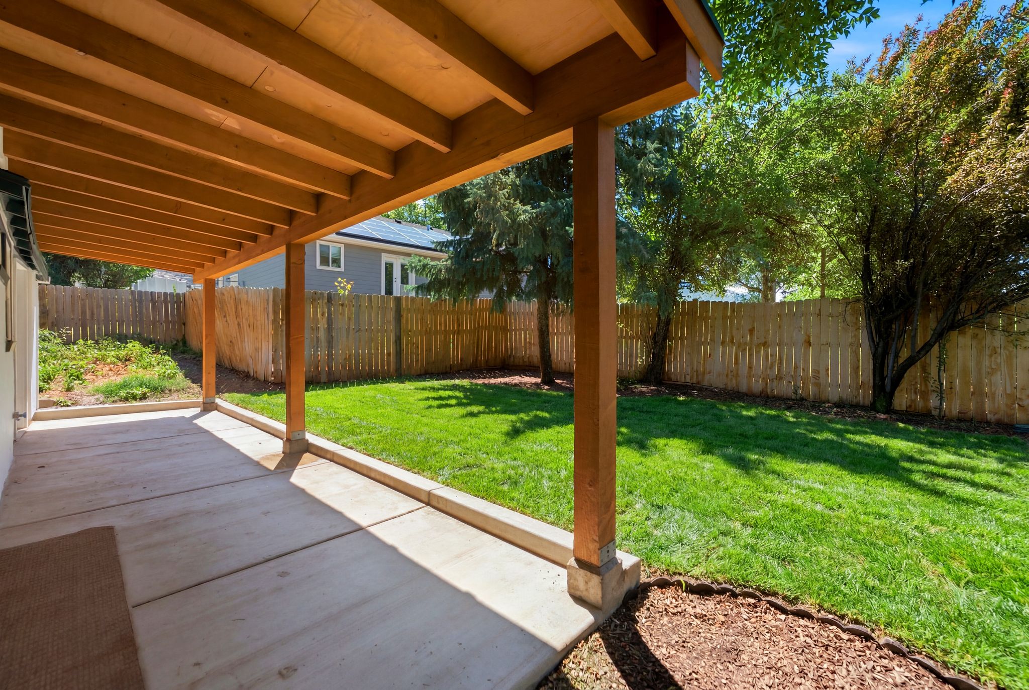 Expansive covered patio featuring a concrete slab and wood beam ceiling