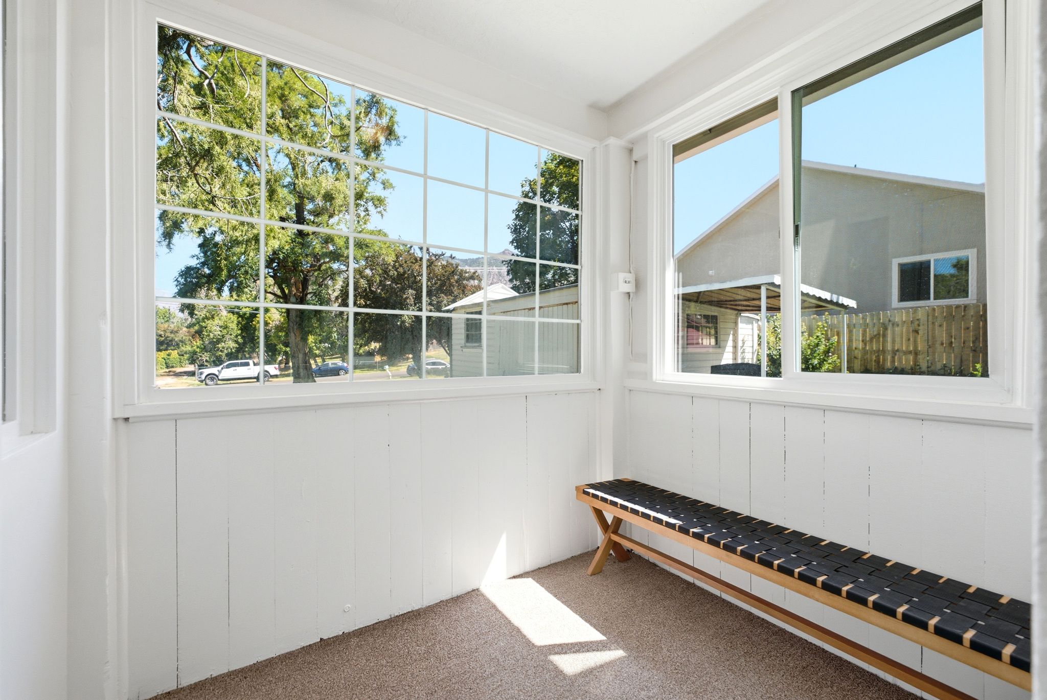 Sunroom featuring white paneled walls, multiple large windows, and a textured carpet flooring