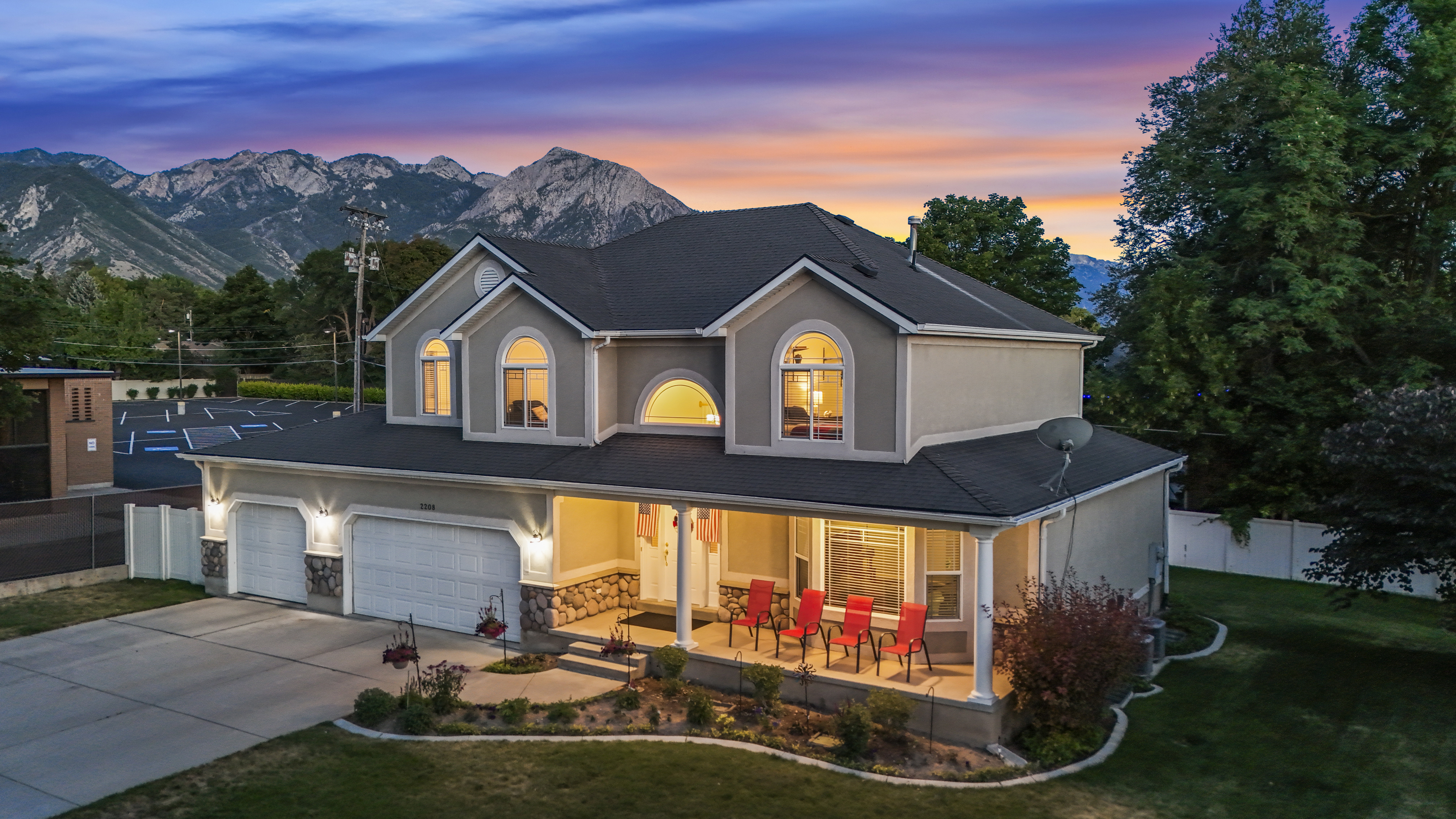 Two-story stucco property featuring a dark shingle roof and prominent arched windows