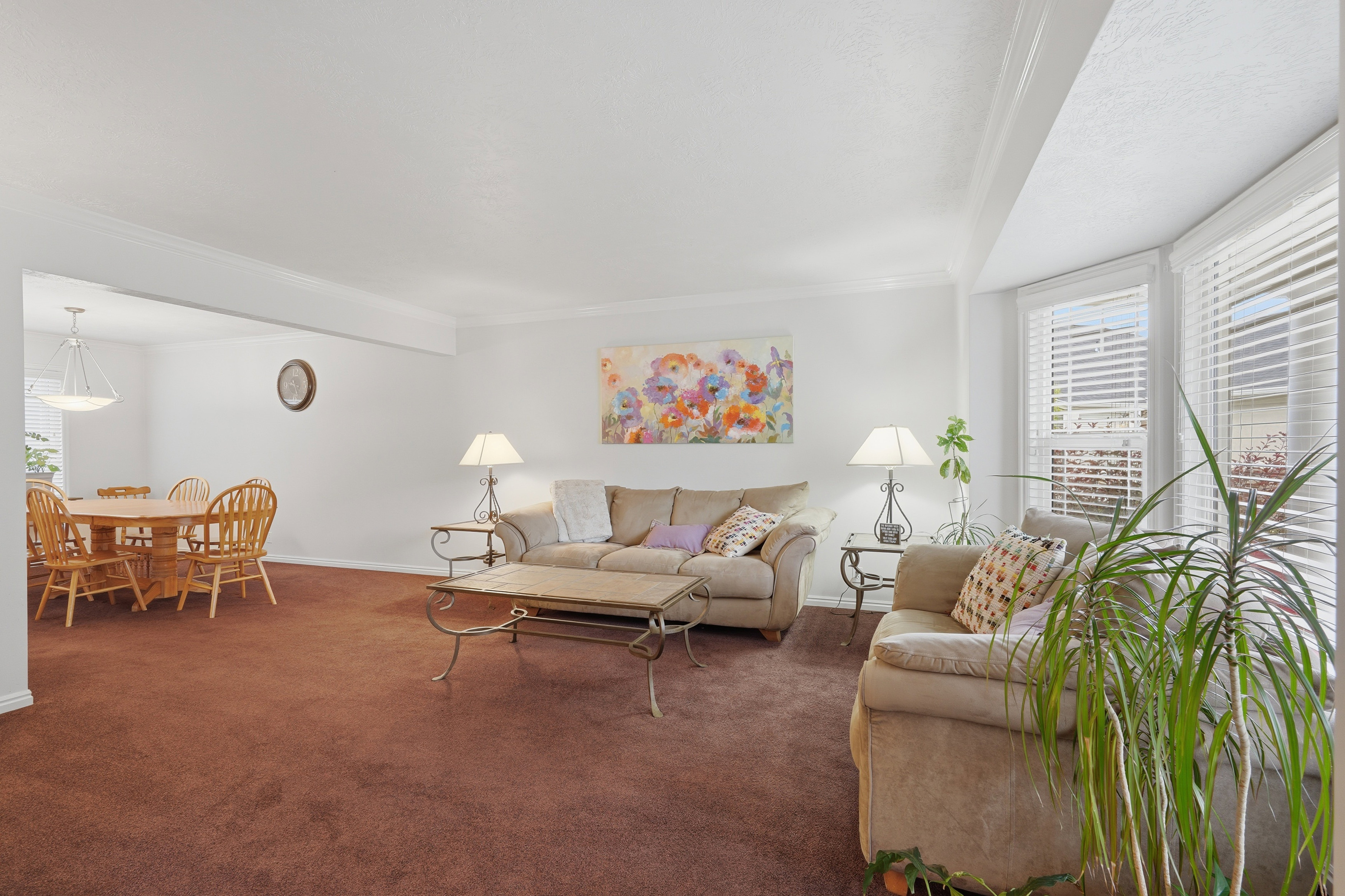 Bay window with white blinds, crown molding, cased opening to dining area, recessed lighting, and neutral wall color