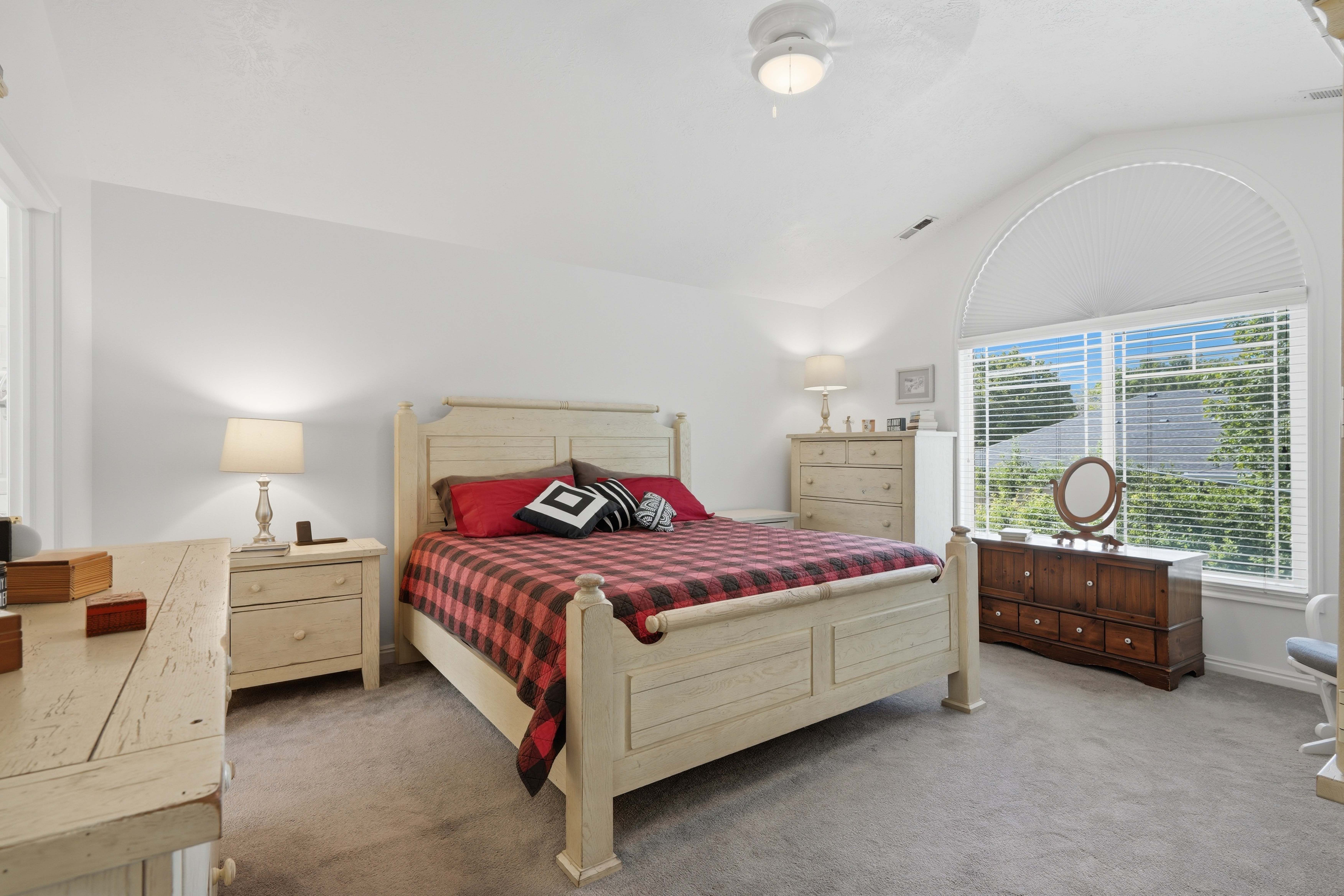 Vaulted ceilings above a large window featuring an arched transom and horizontal blinds