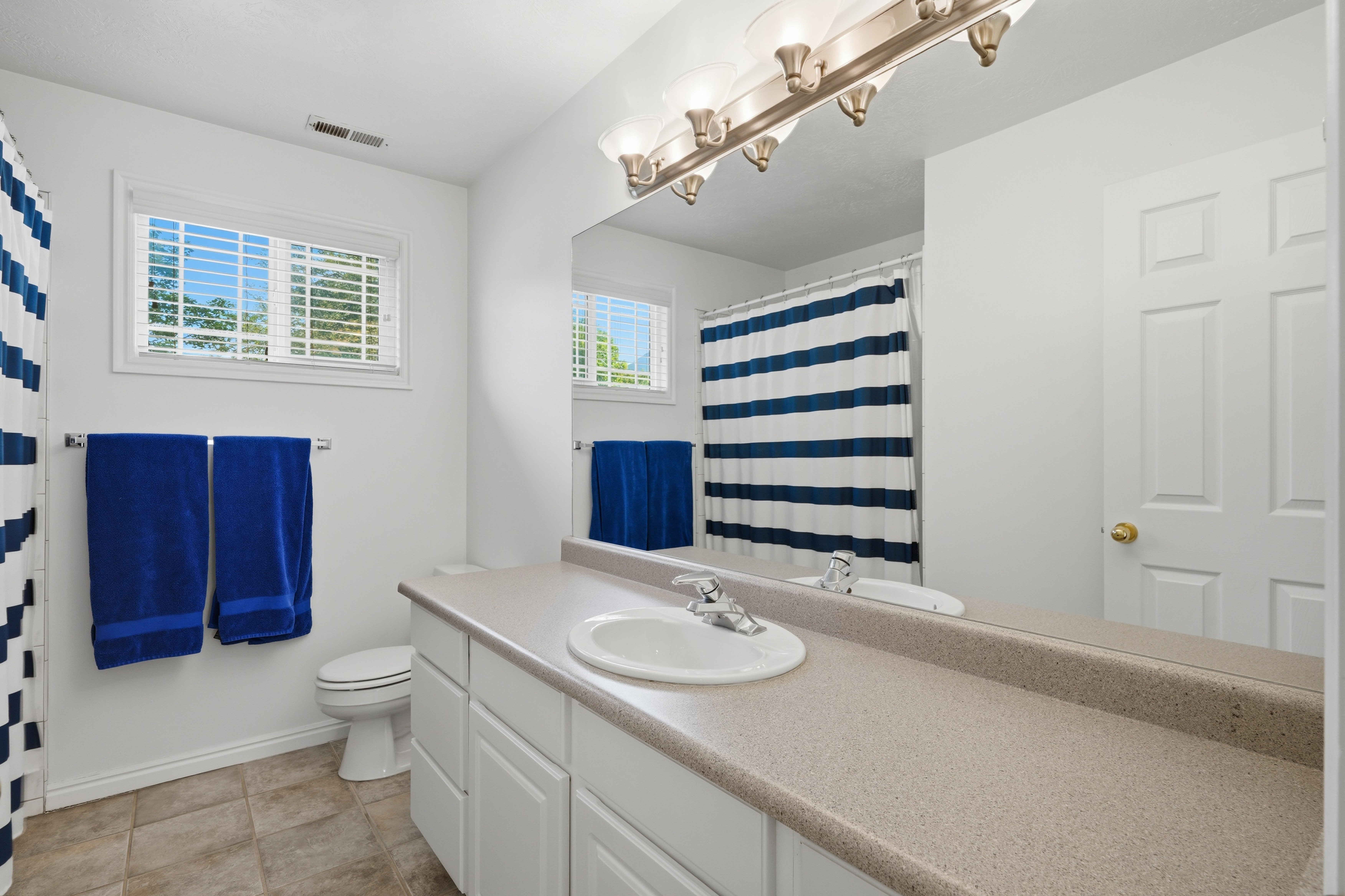 Bathroom featuring a single vanity with an integrated sink, expansive mirror, and tile flooring