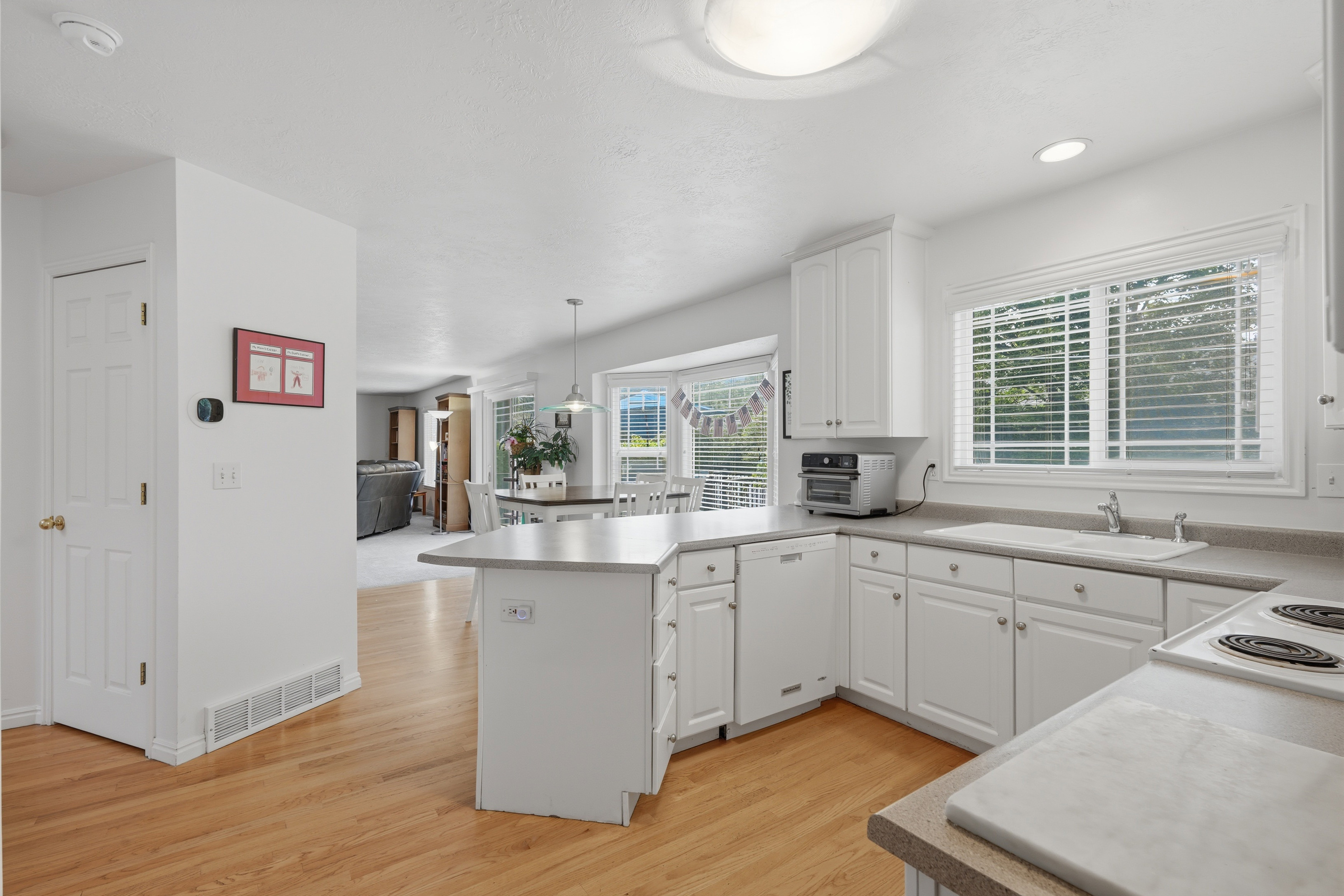 Kitchen featuring white cabinetry, light-toned countertops, and wood-finish flooring