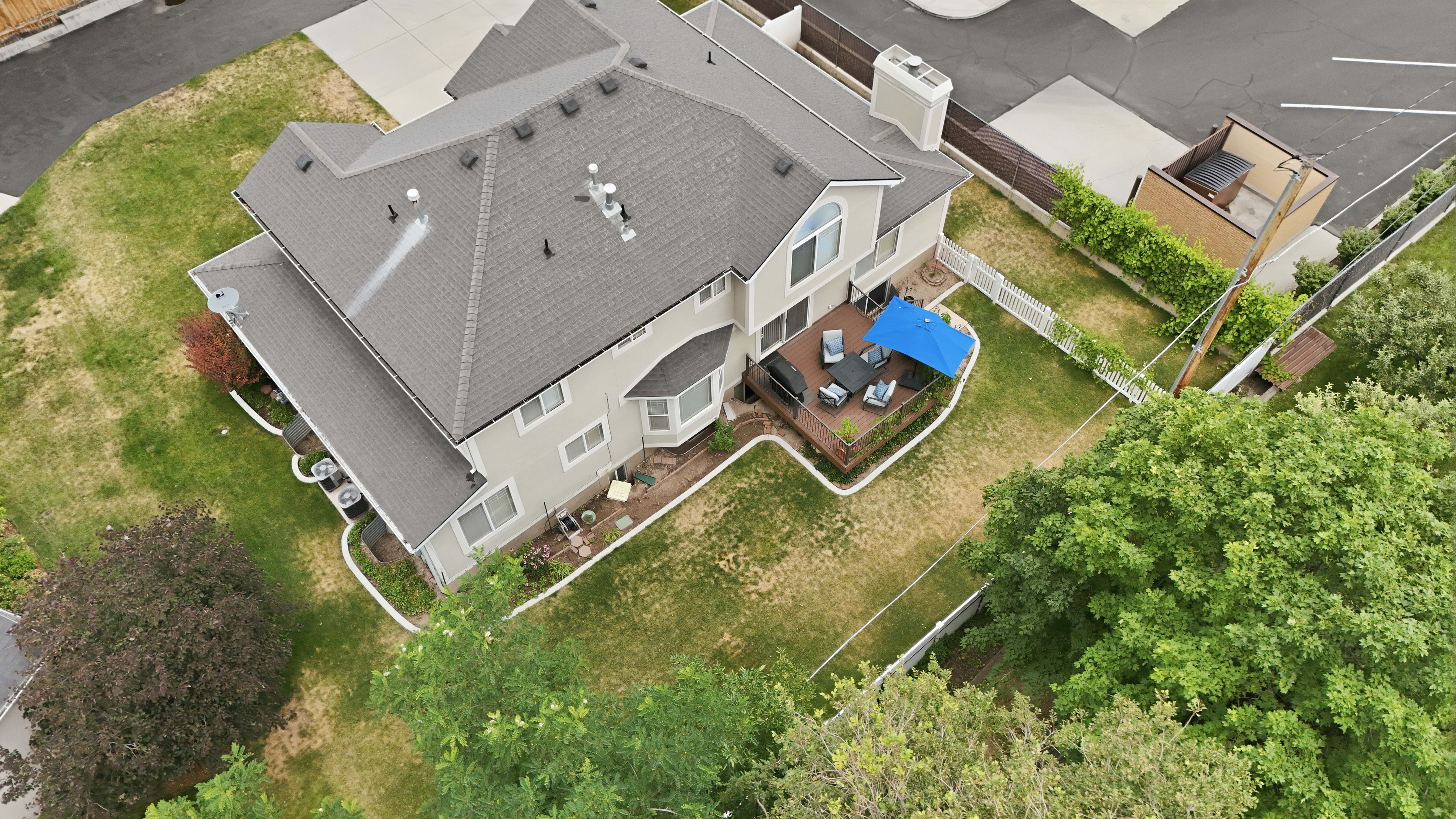 Rear exterior with a multi-level wood deck, bay windows, and mature perimeter trees