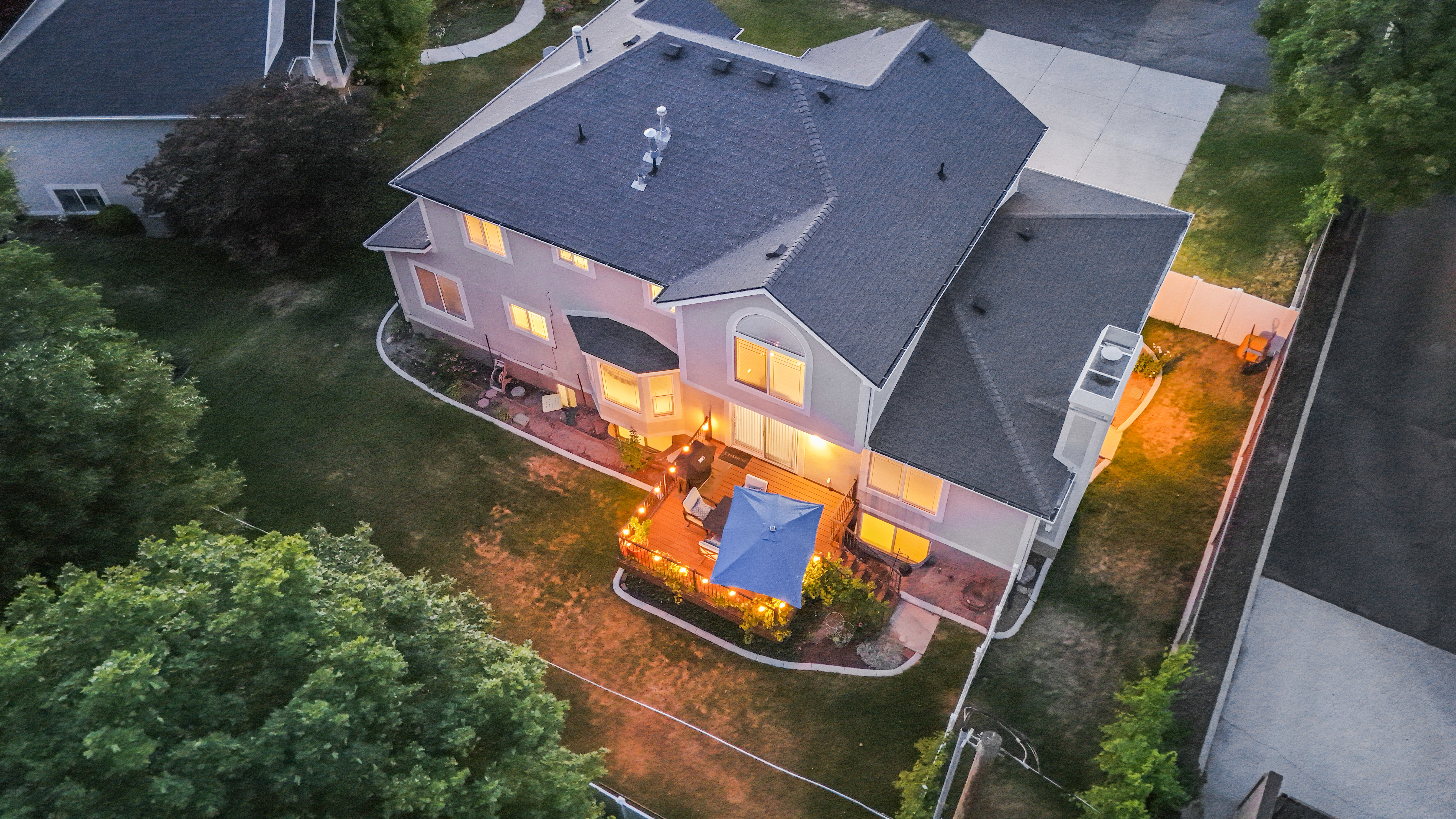 Rear exterior of a multi-story residence featuring a dark shingle roof, stucco siding, and multiple windows