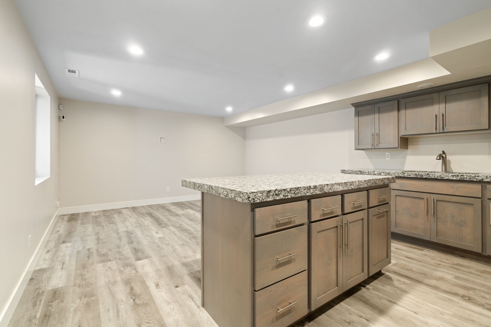 Kitchenette featuring an island with granite countertops, wood-finish cabinetry, and recessed lighting