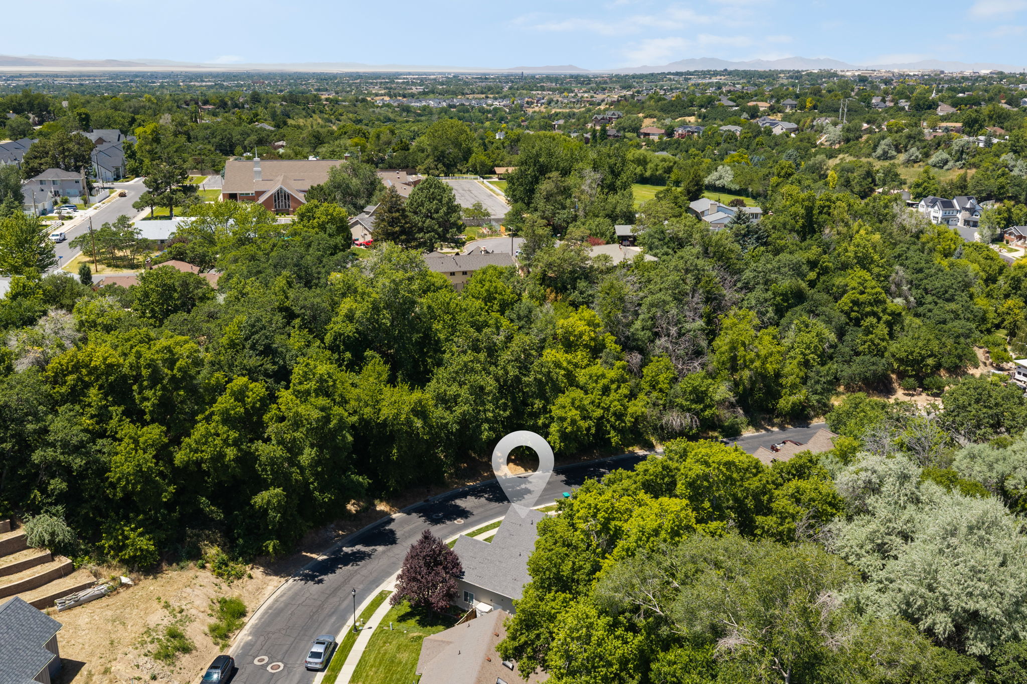 Aerial perspective showcasing a residential area with extensive tree coverage and distant mountains
