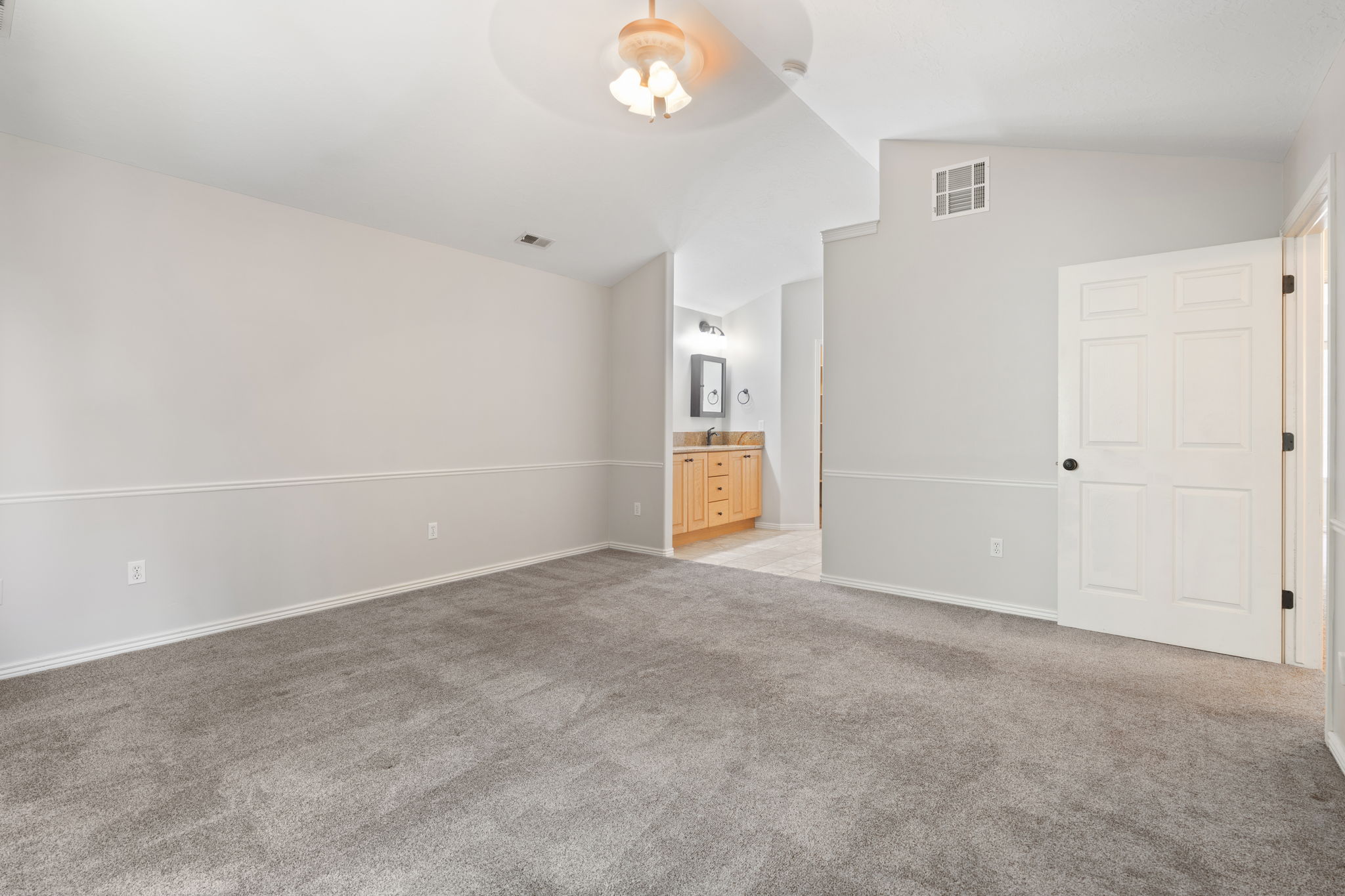 Spacious room featuring vaulted ceilings, a ceiling fan with integrated lighting, and a neutral carpeted floor