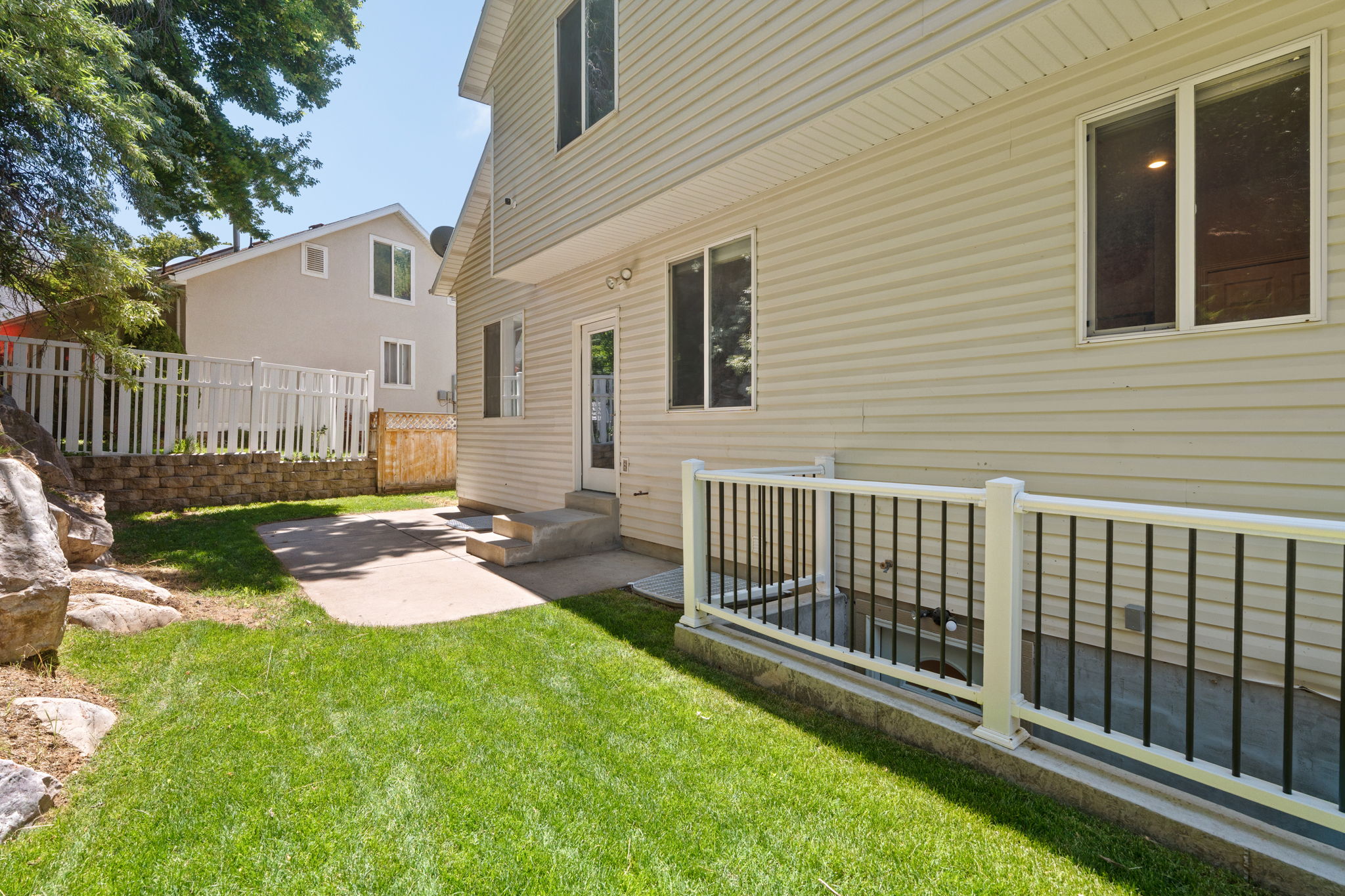 Manicured lawn with a concrete patio and retaining wall