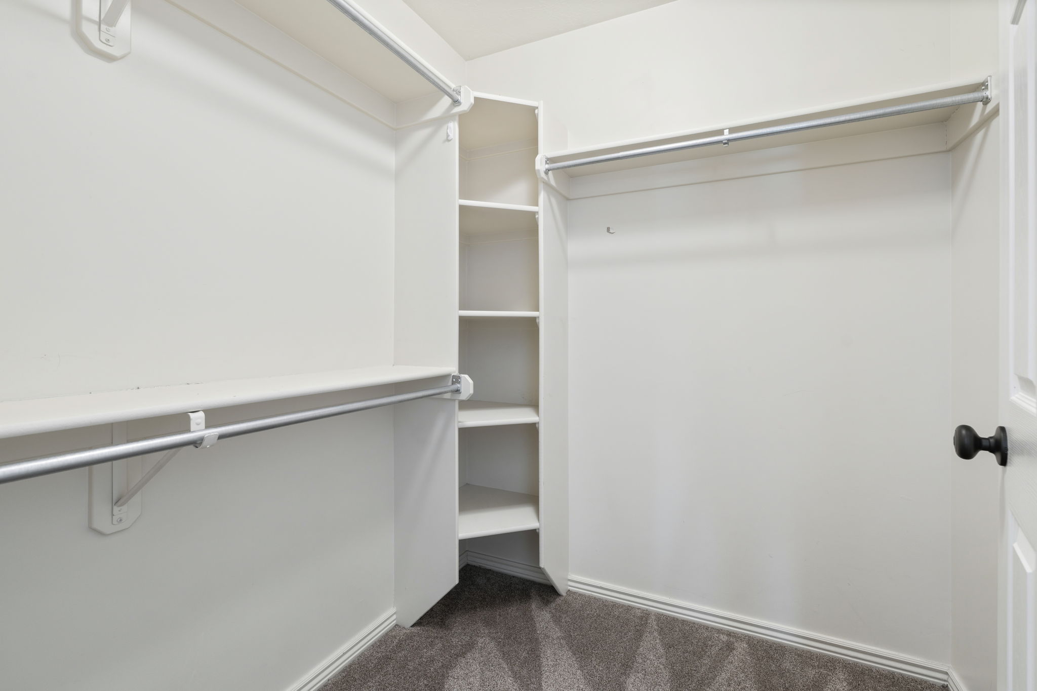 Walk-in closet featuring built-in shelving and multiple hanging rods