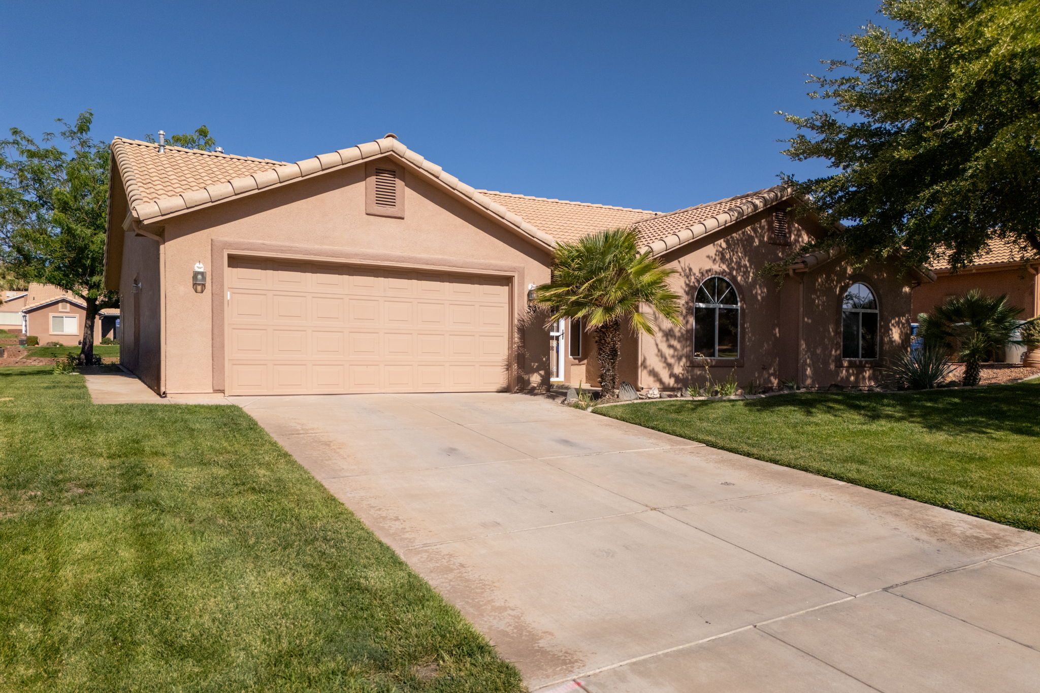 Stucco exterior residence featuring a two-car garage, concrete driveway, and arched windows