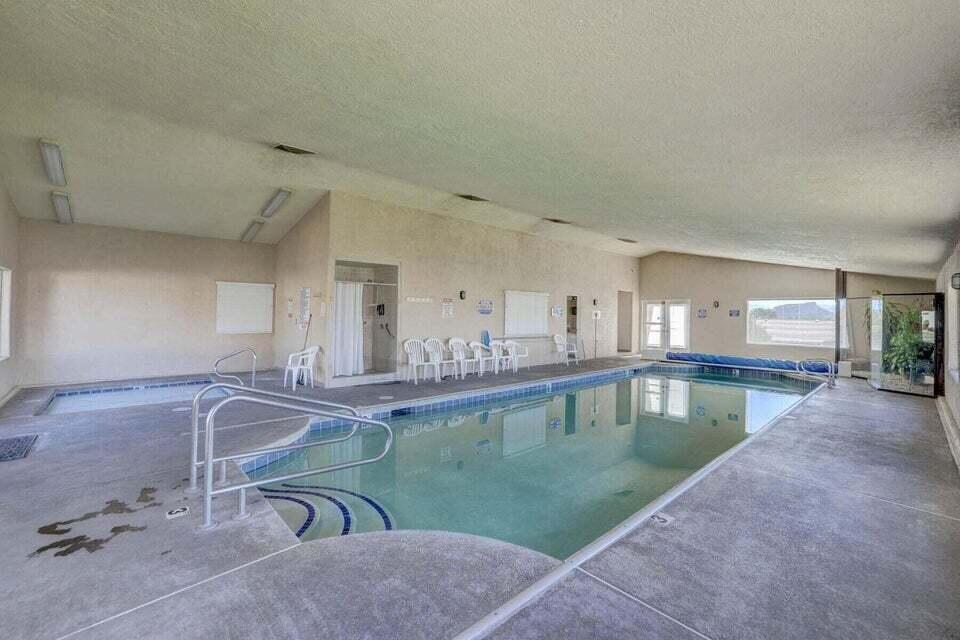 Indoor swimming pool with concrete decking, a built-in spa, and integrated lighting
